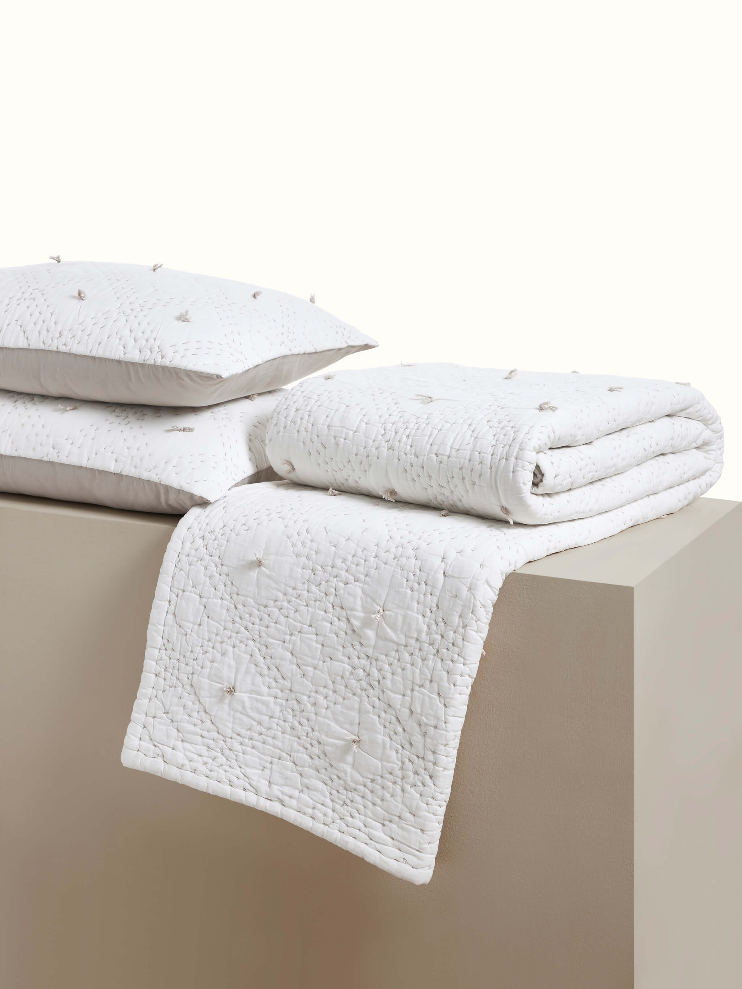 Angled view of Nihar ivory cotton bedspread with diamond embroidery and razai texture