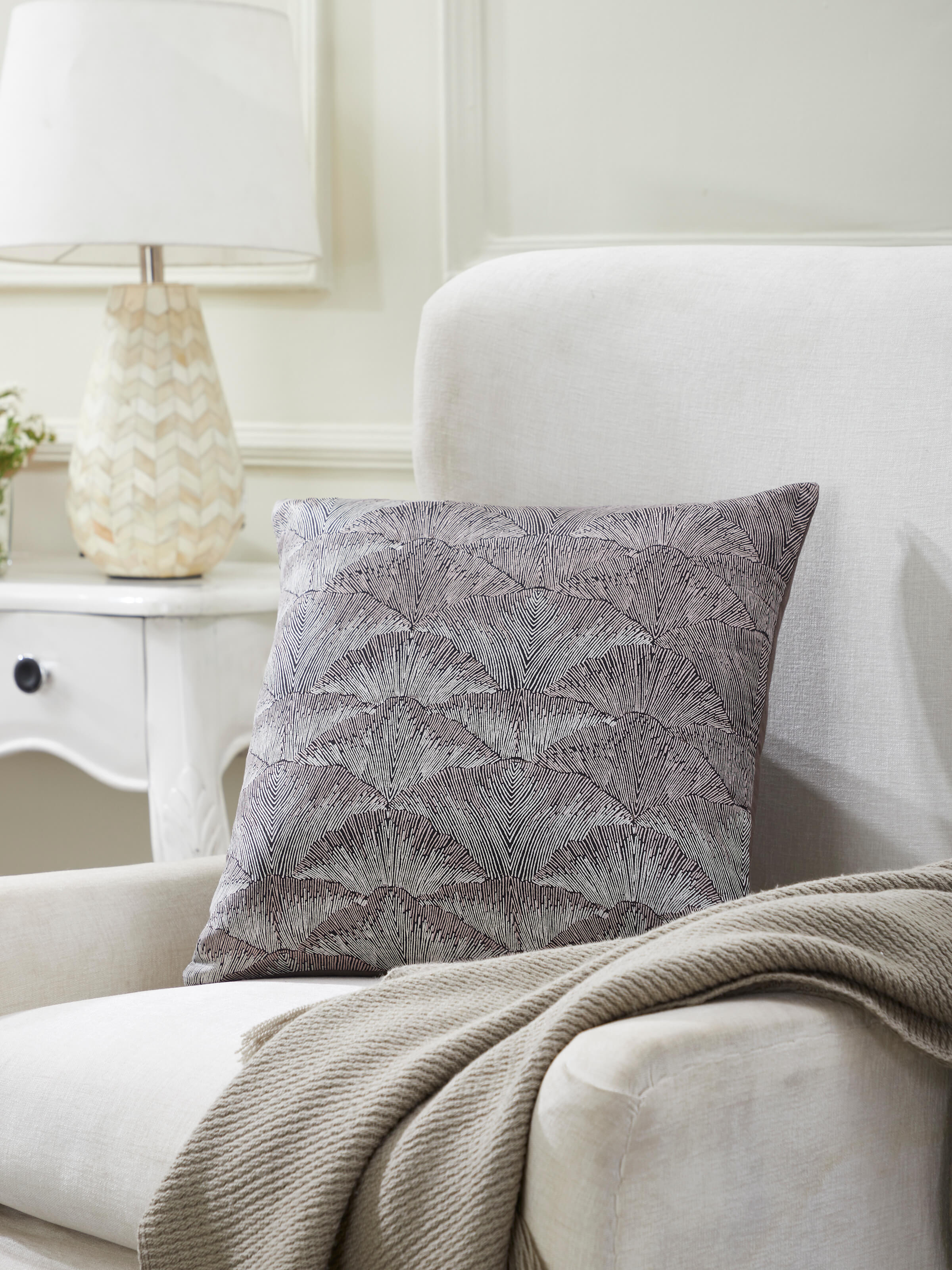 Lifestyle view of Parvat brown textured silk cushion cover styled on a beige sofa with neutral furnishings.