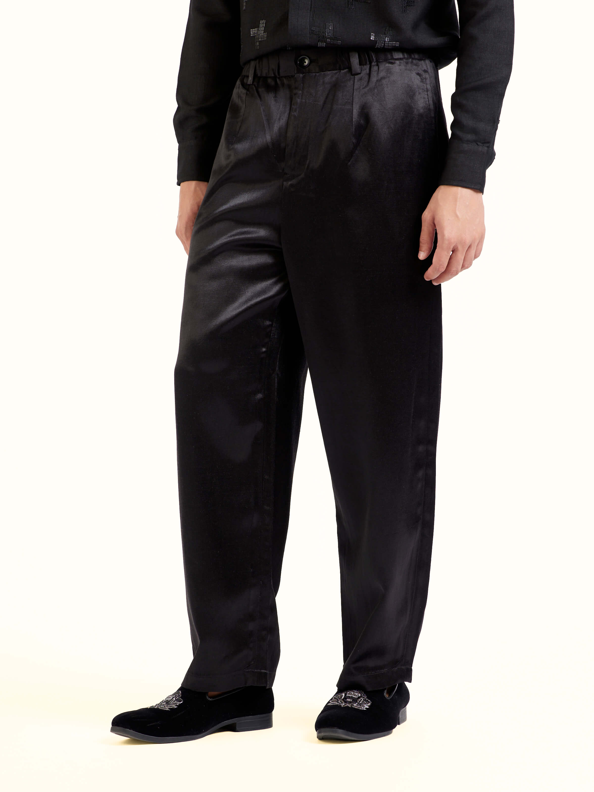 Angled view of black straight cut mashru pants emphasizing mashru fabric texture