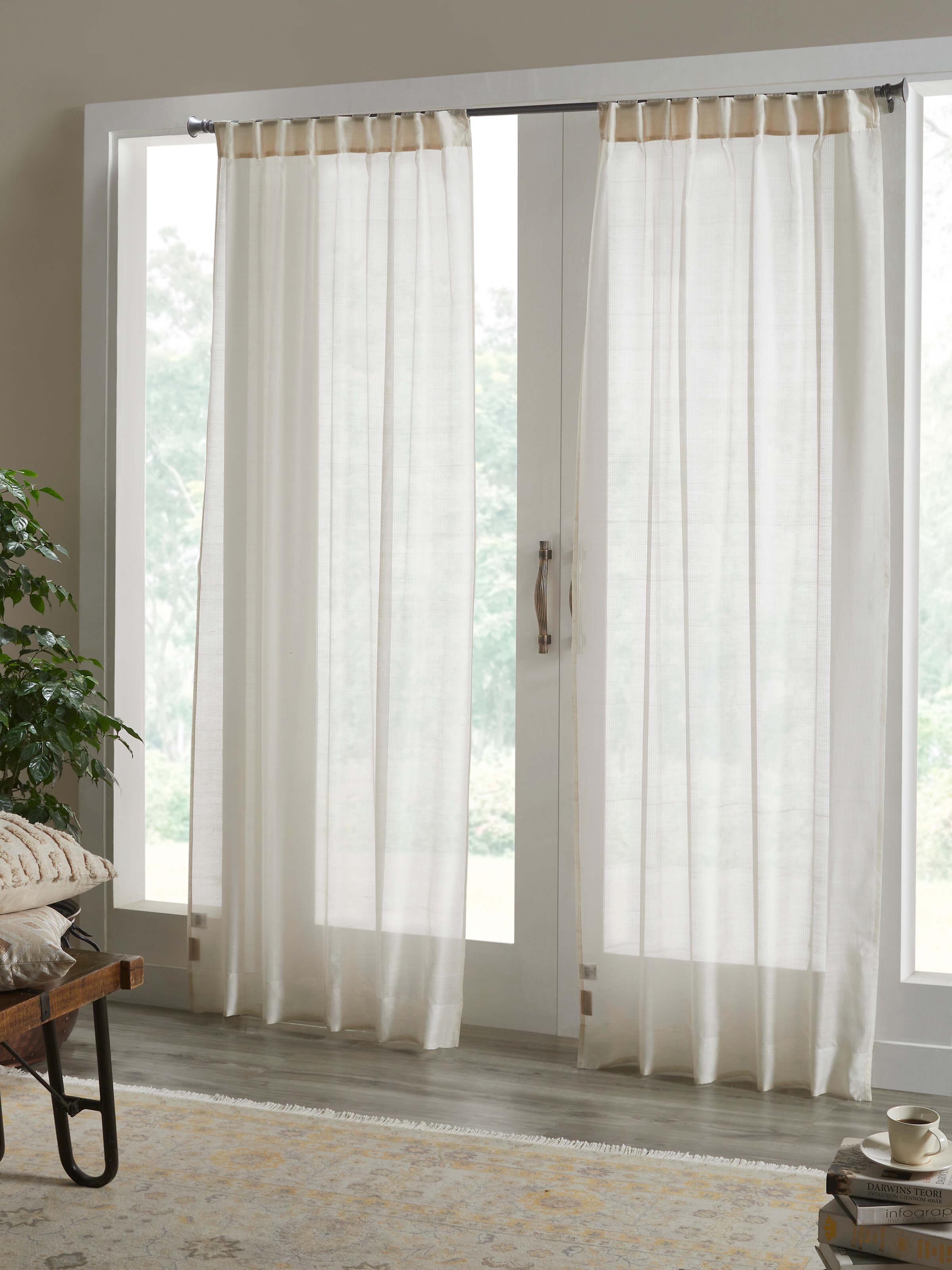 Elegant room setting with floor-length ivory curtain filtering natural light.