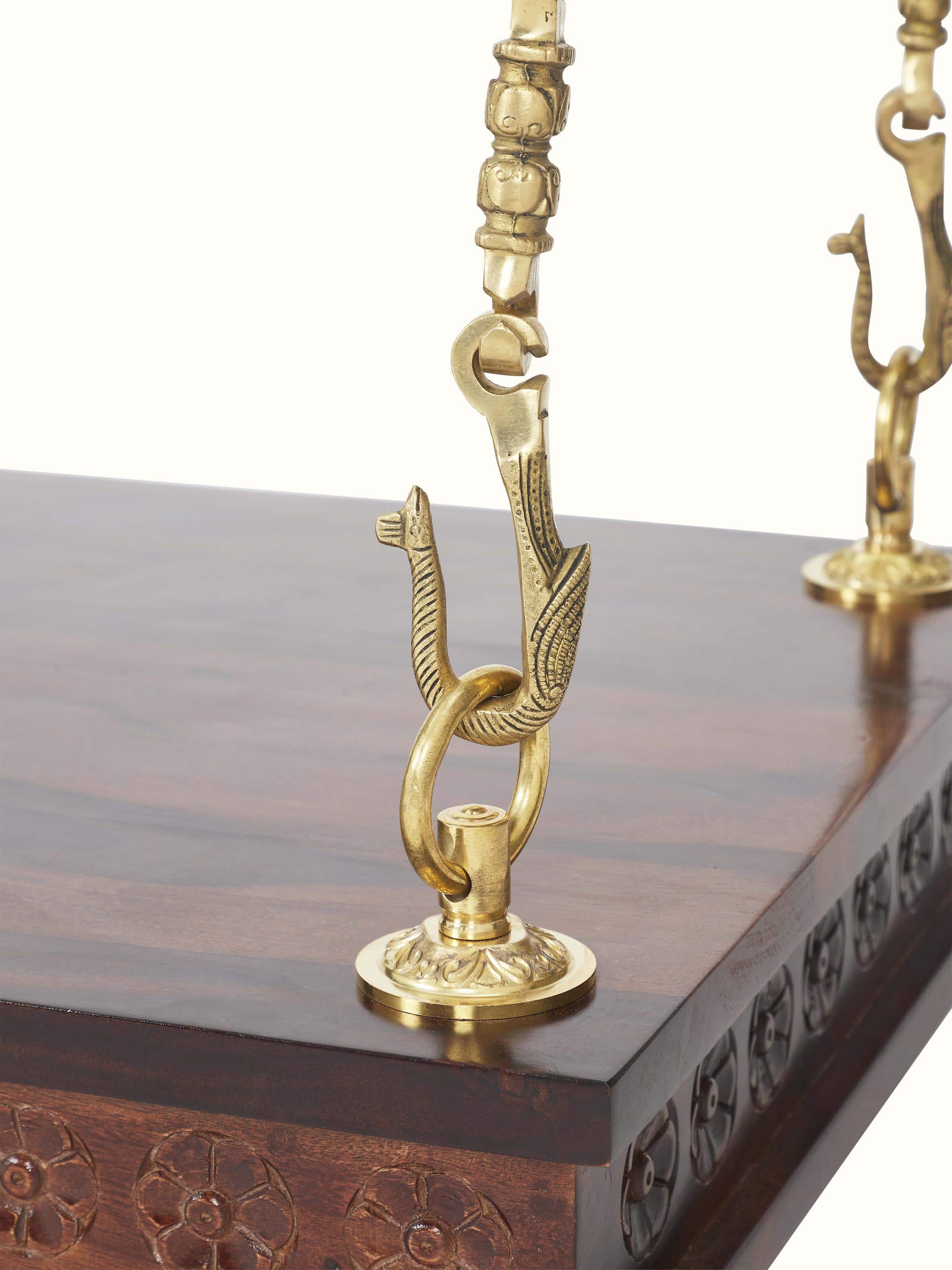 Close-up of the brass detailing on the Sheesham wood swing, emphasizing the ornamental craftsmanship.