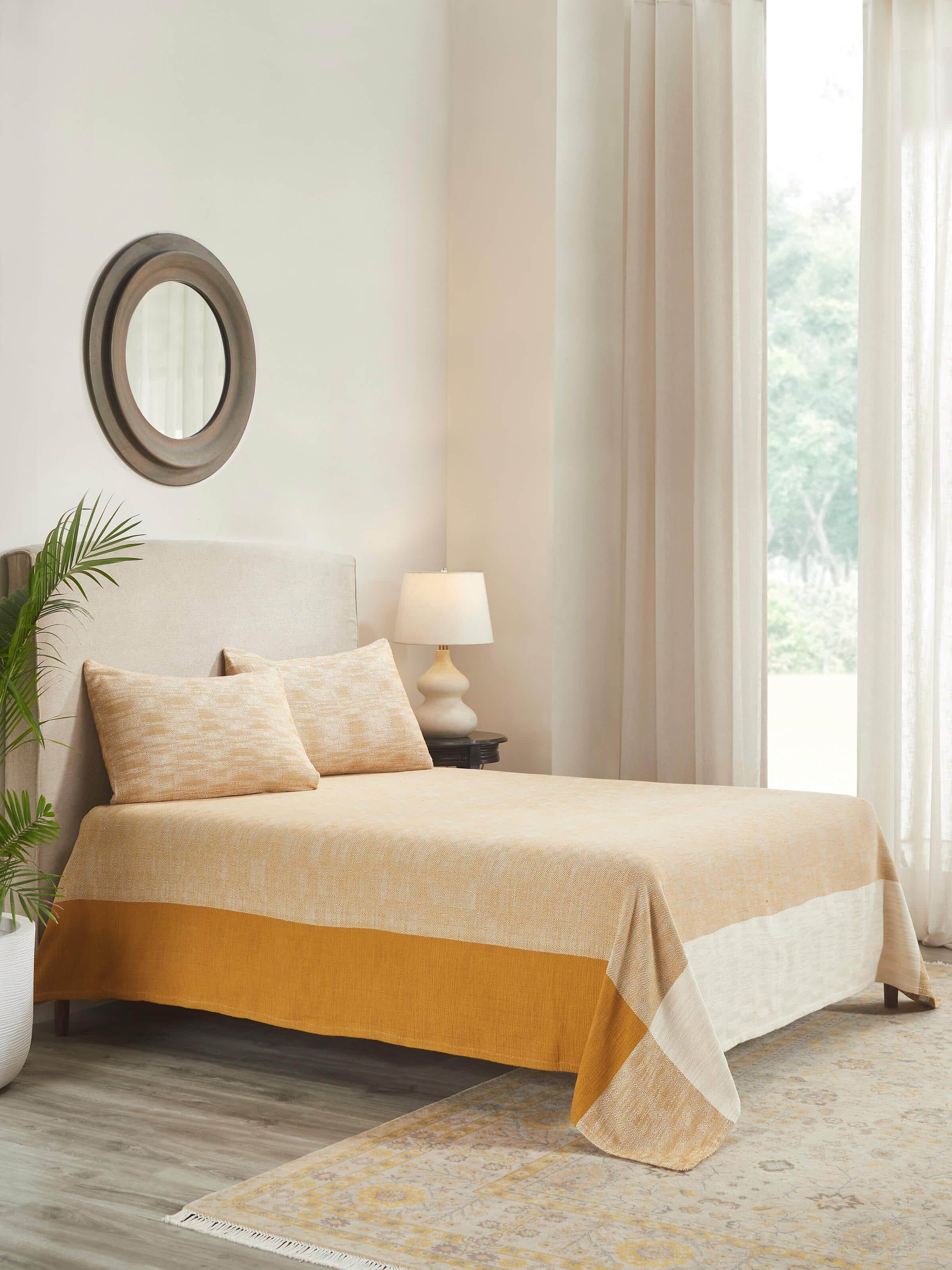 Lifestyle shot: Yellow cotton bedspread styled in airy bedroom with handloom simplicity.