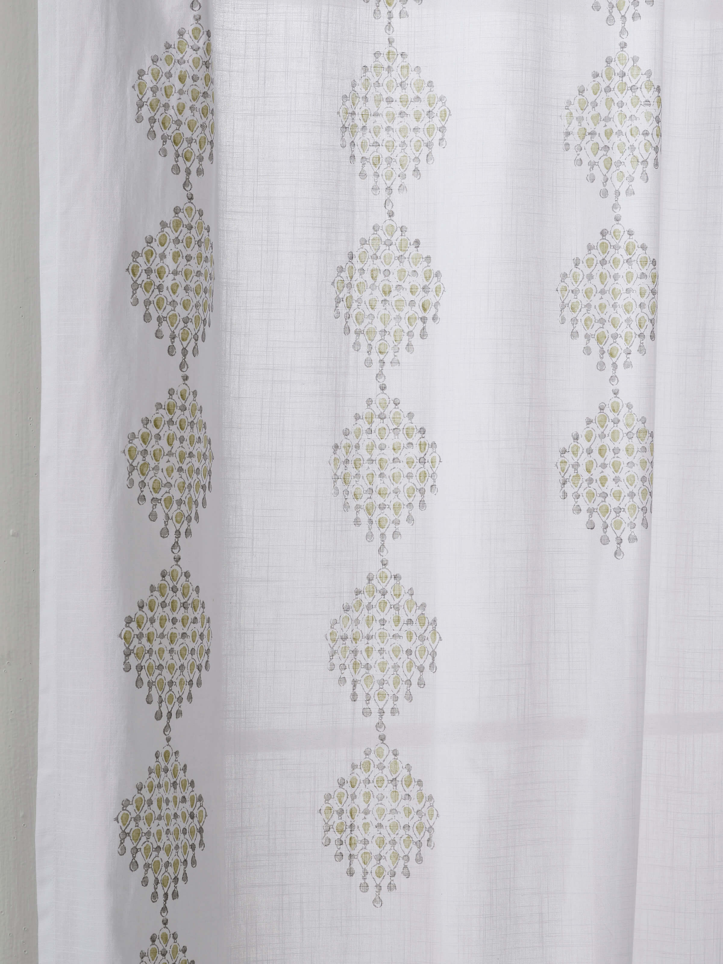 Detailed shot of Sanganeri block print on cotton curtain in modern green geometric pattern.