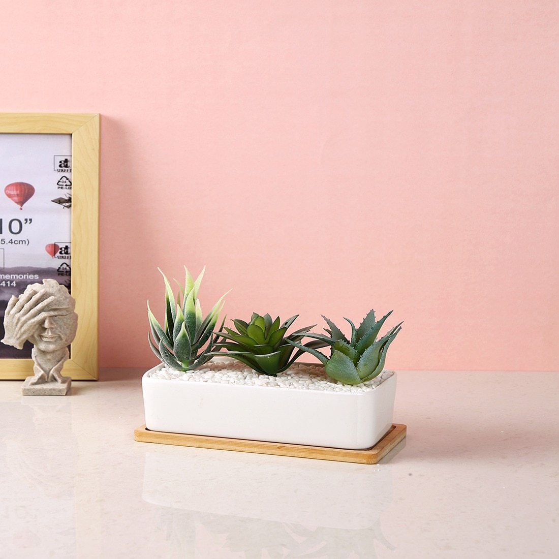 Artificial Faux Plants In A Ceramic Pot With A Wooden Plate