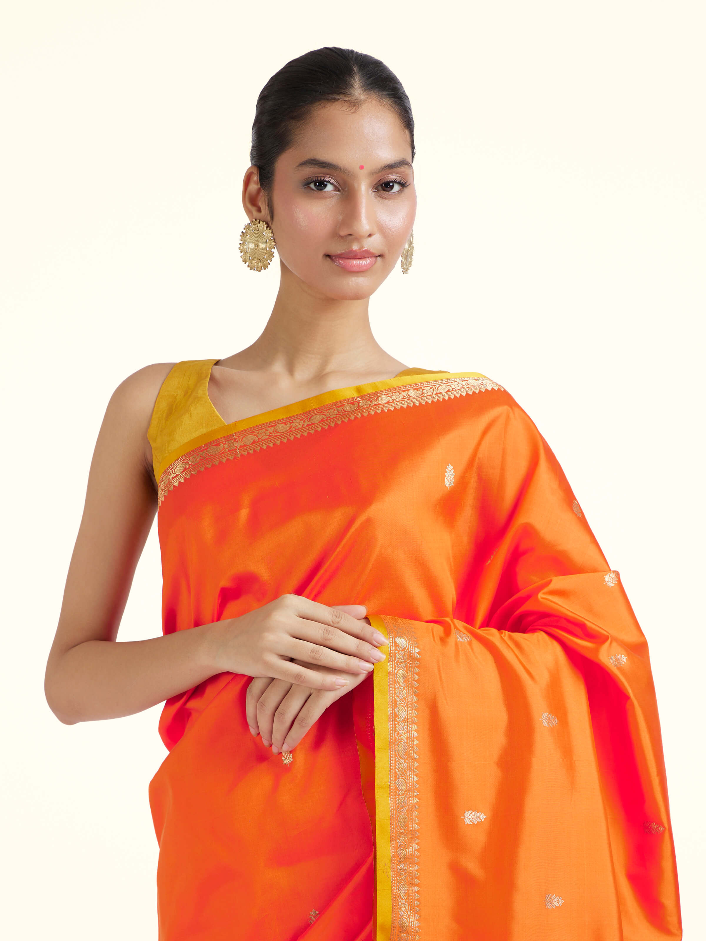 Angled view of orange mulberry katan silk Banarasi saree showcasing traditional zari work