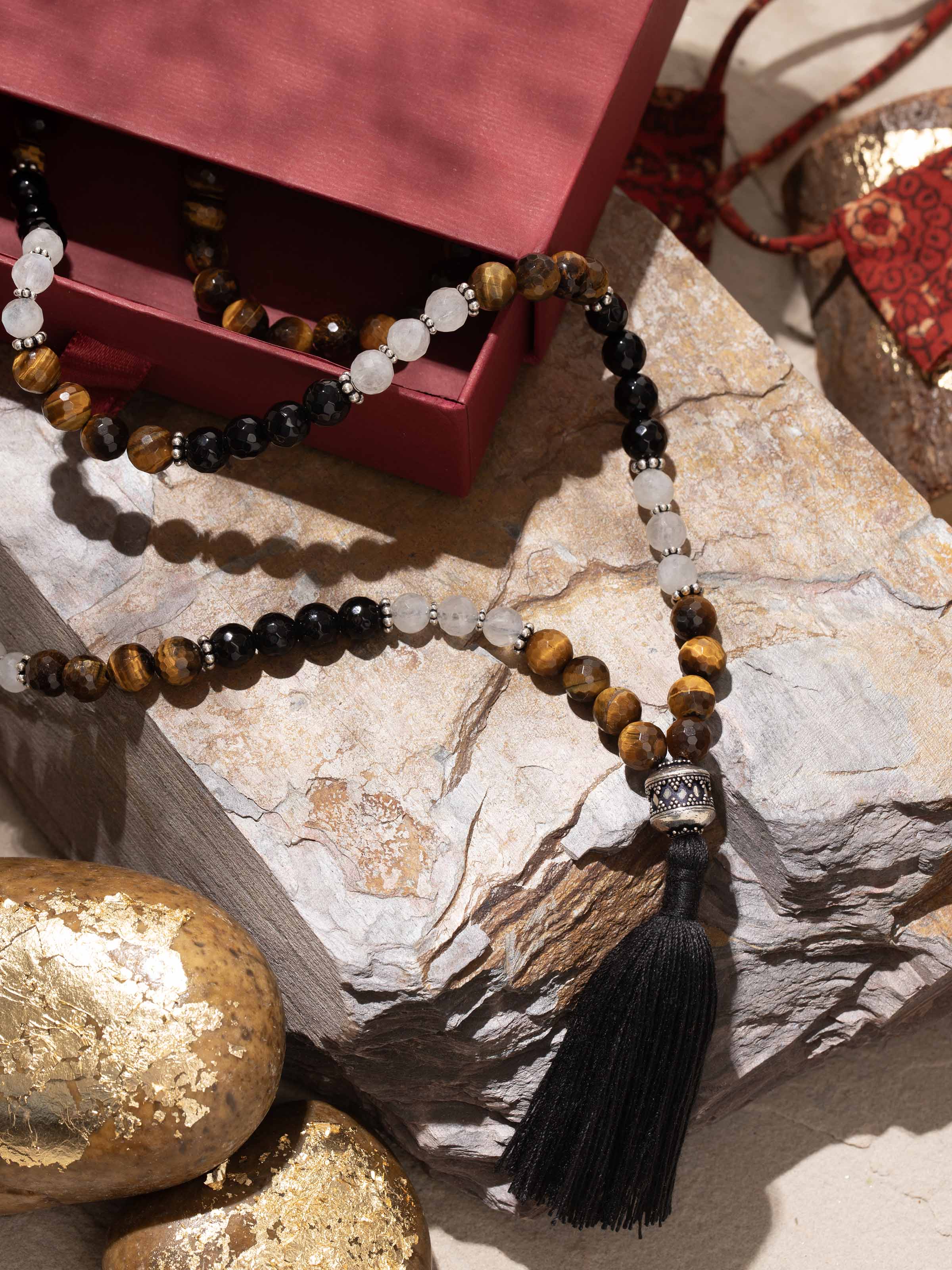 Side view of mala showing natural mix of Onyx, Moonstone, and Tiger Eye on silver thread