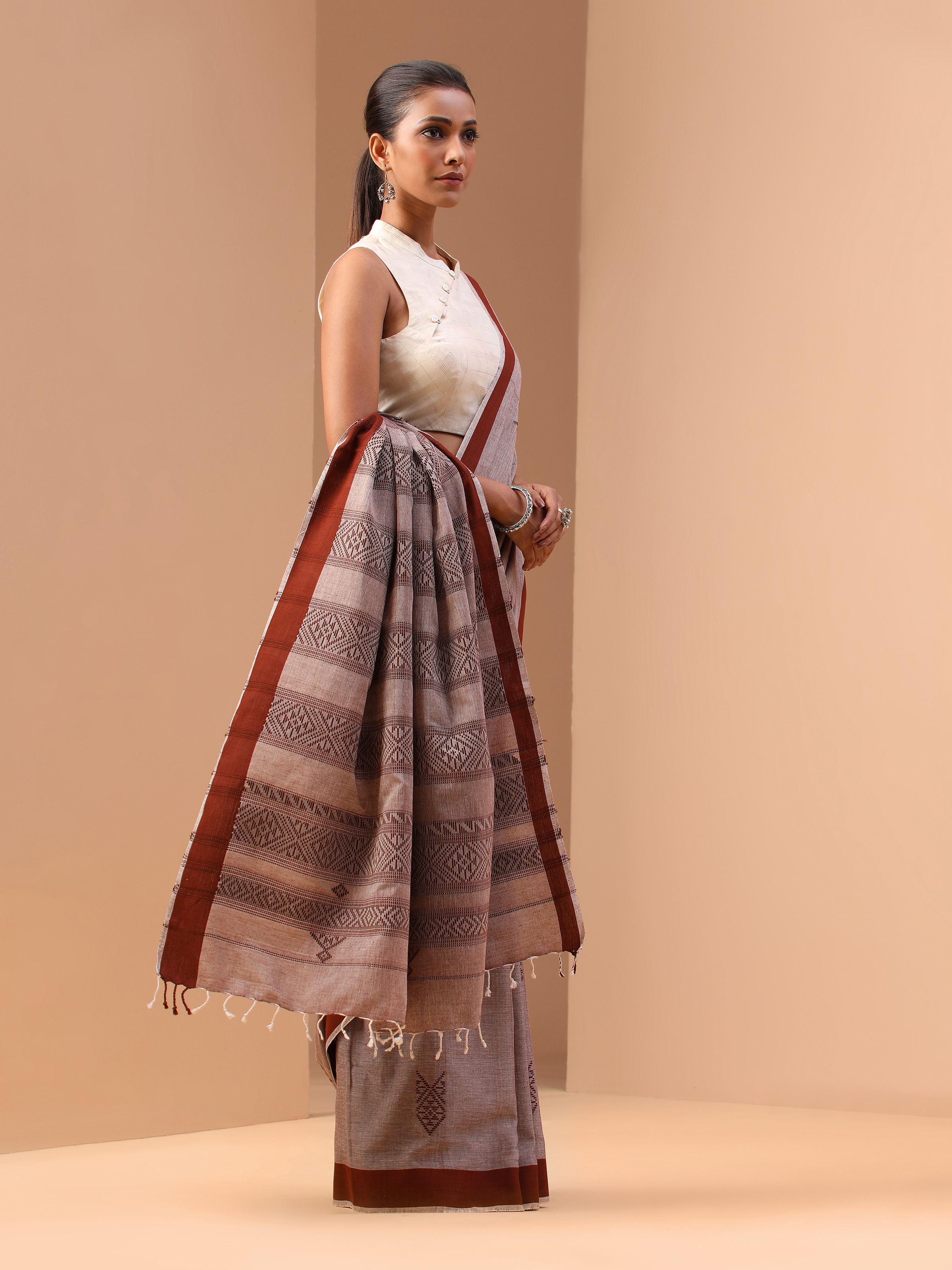 Alternate lifestyle view of brown extra-weft saree showing body motifs and pallu