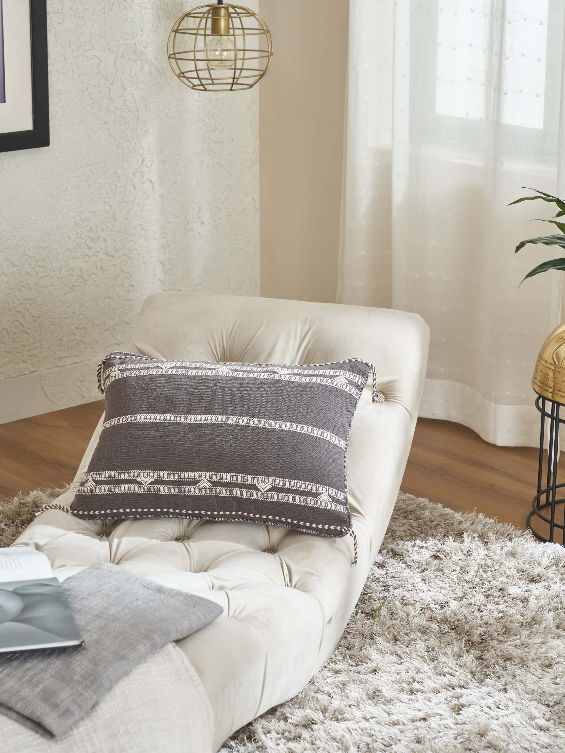 Lifestyle view of Anek Coffee Bhujodi Cushion Cover placed on a beige sofa setting