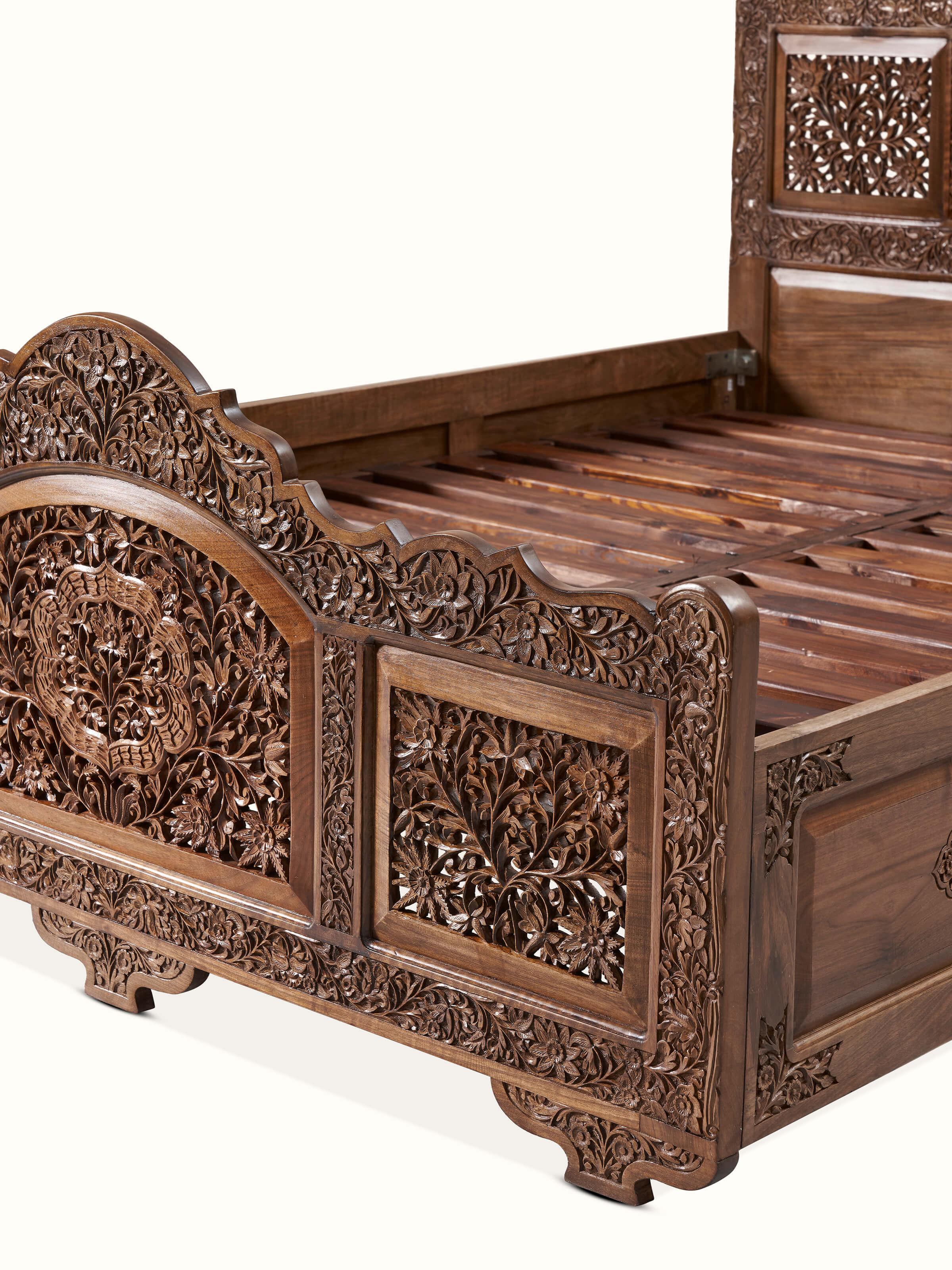 Close-up of the footboard and side rails of carved walnut wood queen size bed, highlighting the wood grain and craftsmanship.