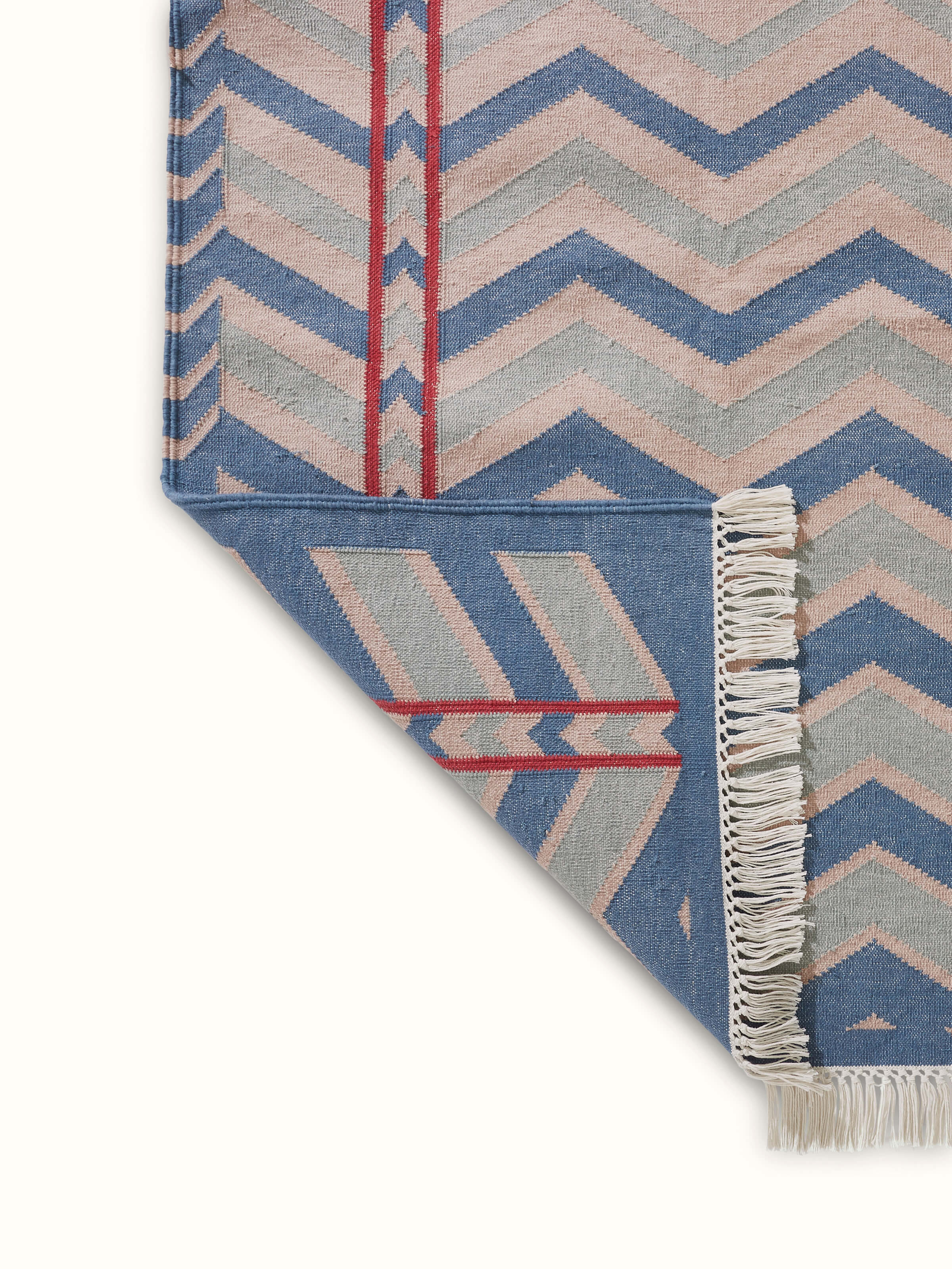 View of Geo chevron gradation blue beige lawan cotton panja dhurrie in a setting, showing its full pattern and style.