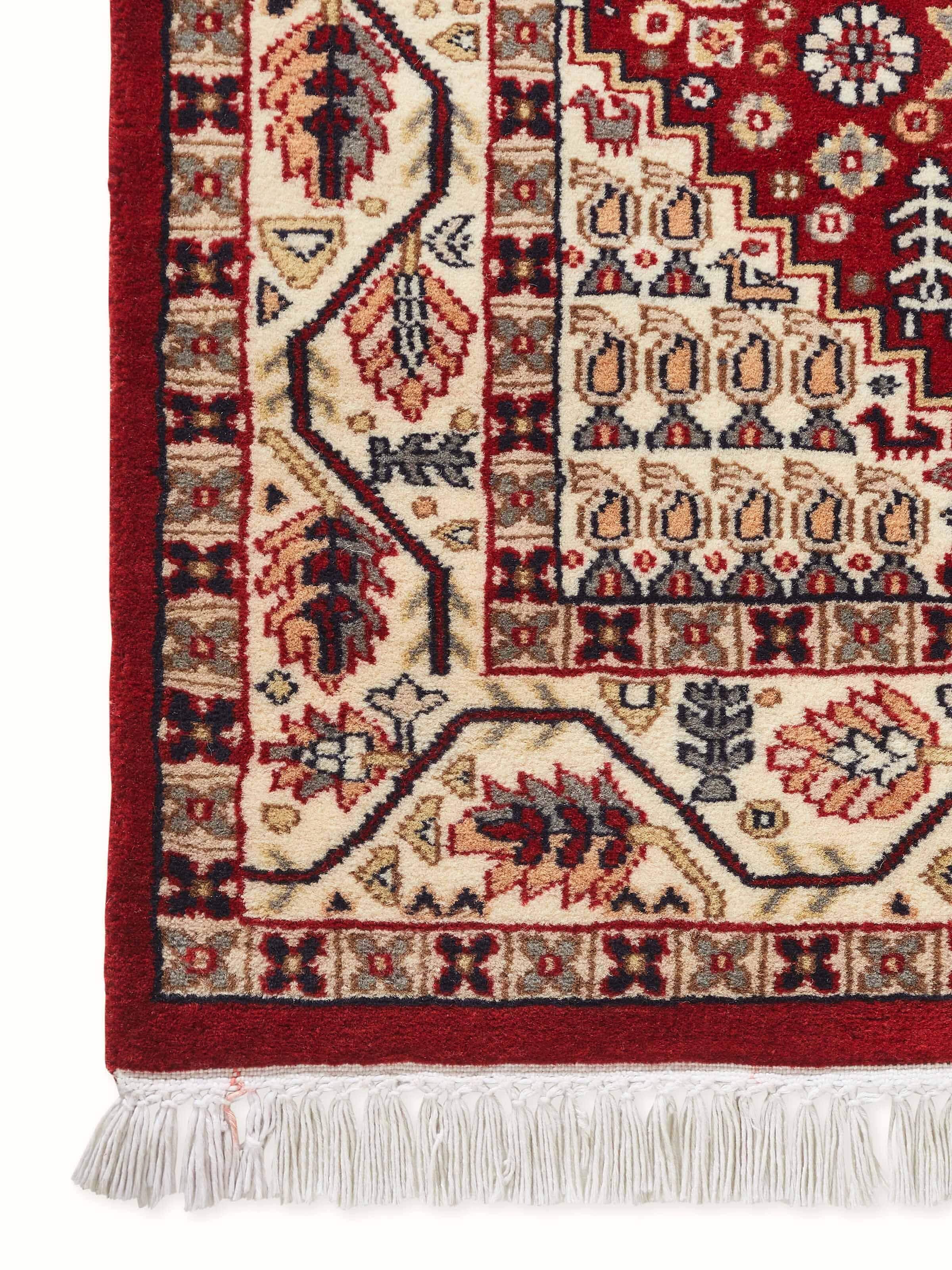 Close-up design view of tribal details in rust Gwalior wool Kazak carpet