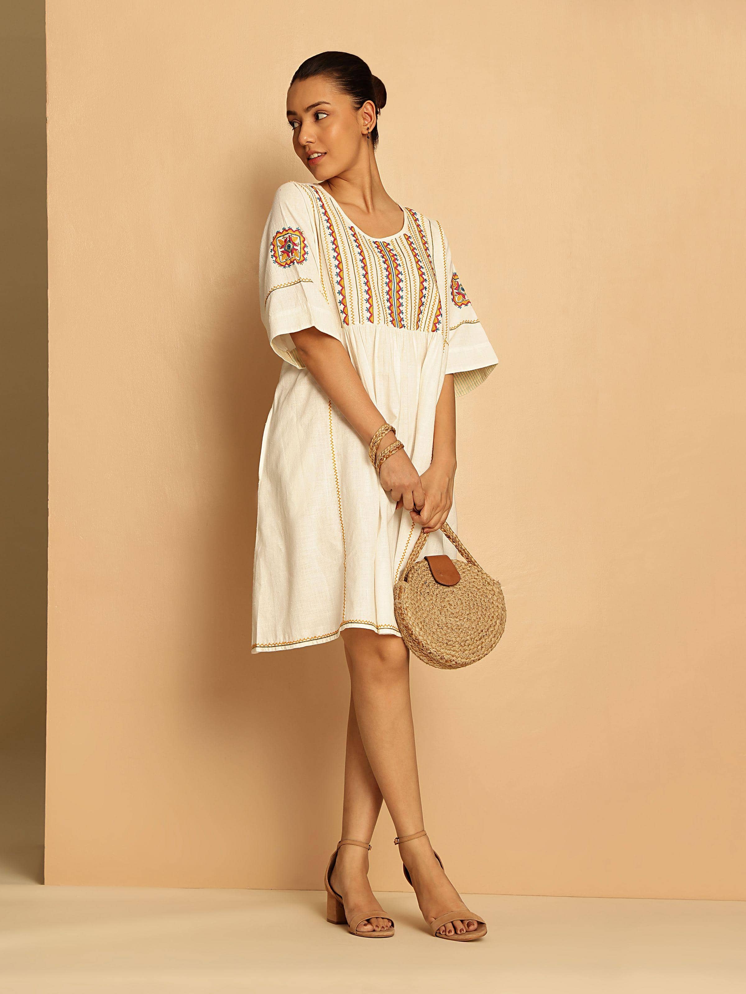 Lifestyle view of off-white short cotton Rajasthani embroidered dress worn by model highlighting embroidery details and comfortable fit.