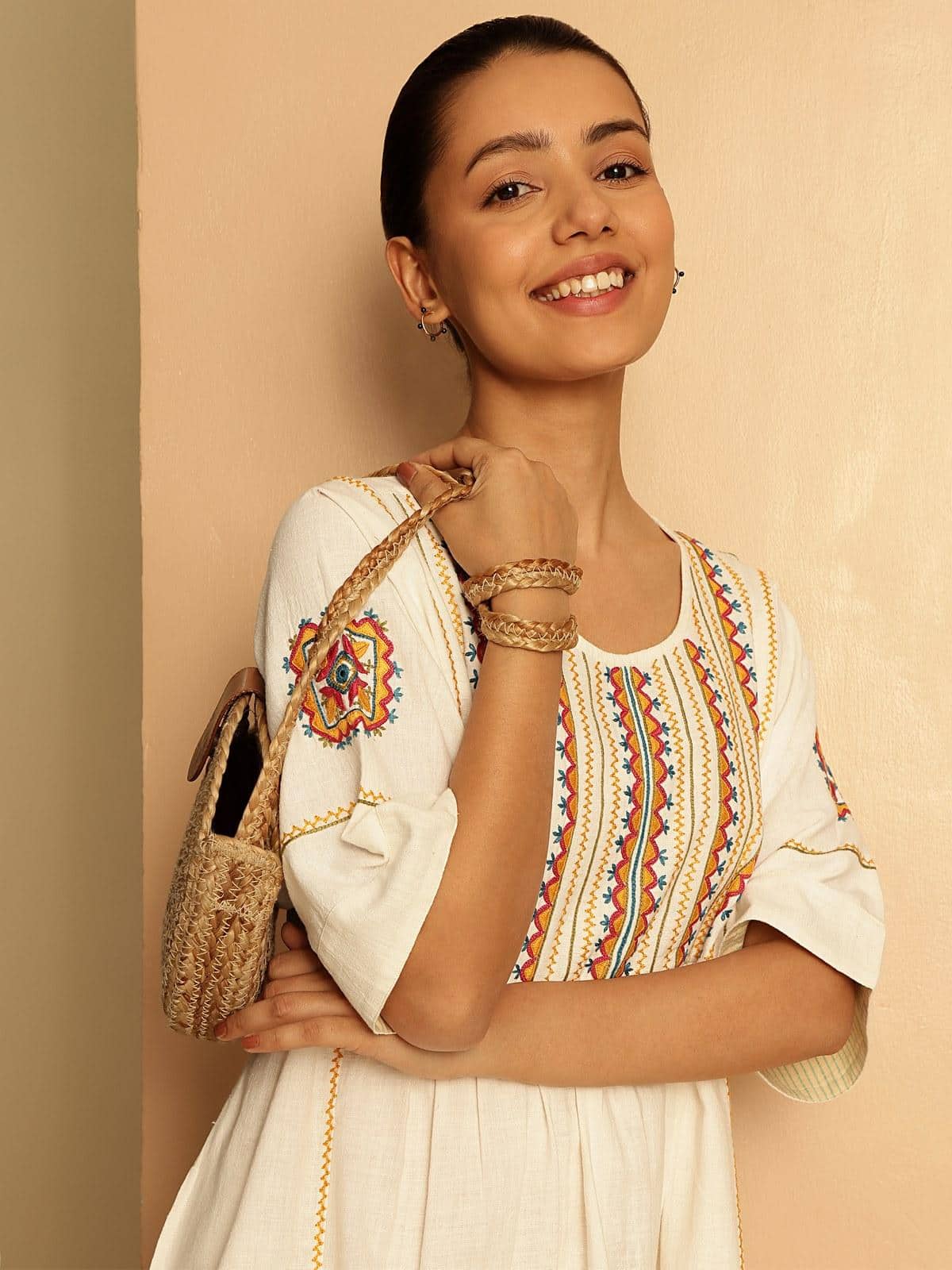 Angled view of off-white short cotton Rajasthani embroidered dress displaying intricate stitching and pattern on lightweight cotton fabric.