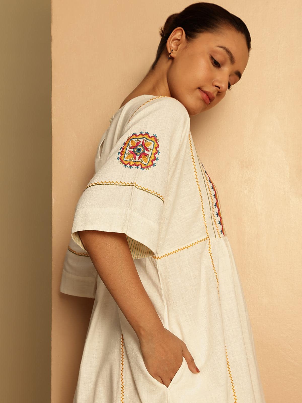 Close-up detail of off-white short cotton Rajasthani embroidered dress emphasizing fine threadwork and embroidery motifs.