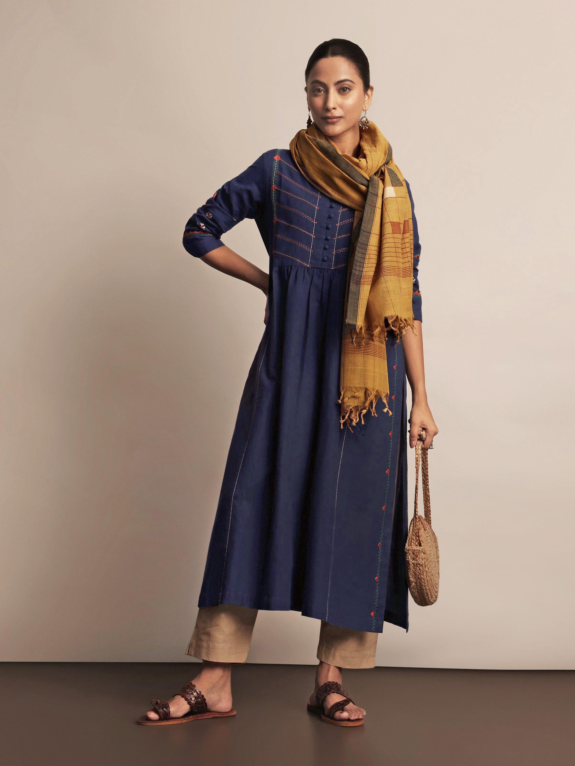 Lifestyle view of indigo embroidered cotton kurta styled with white trousers and ethnic jewelry