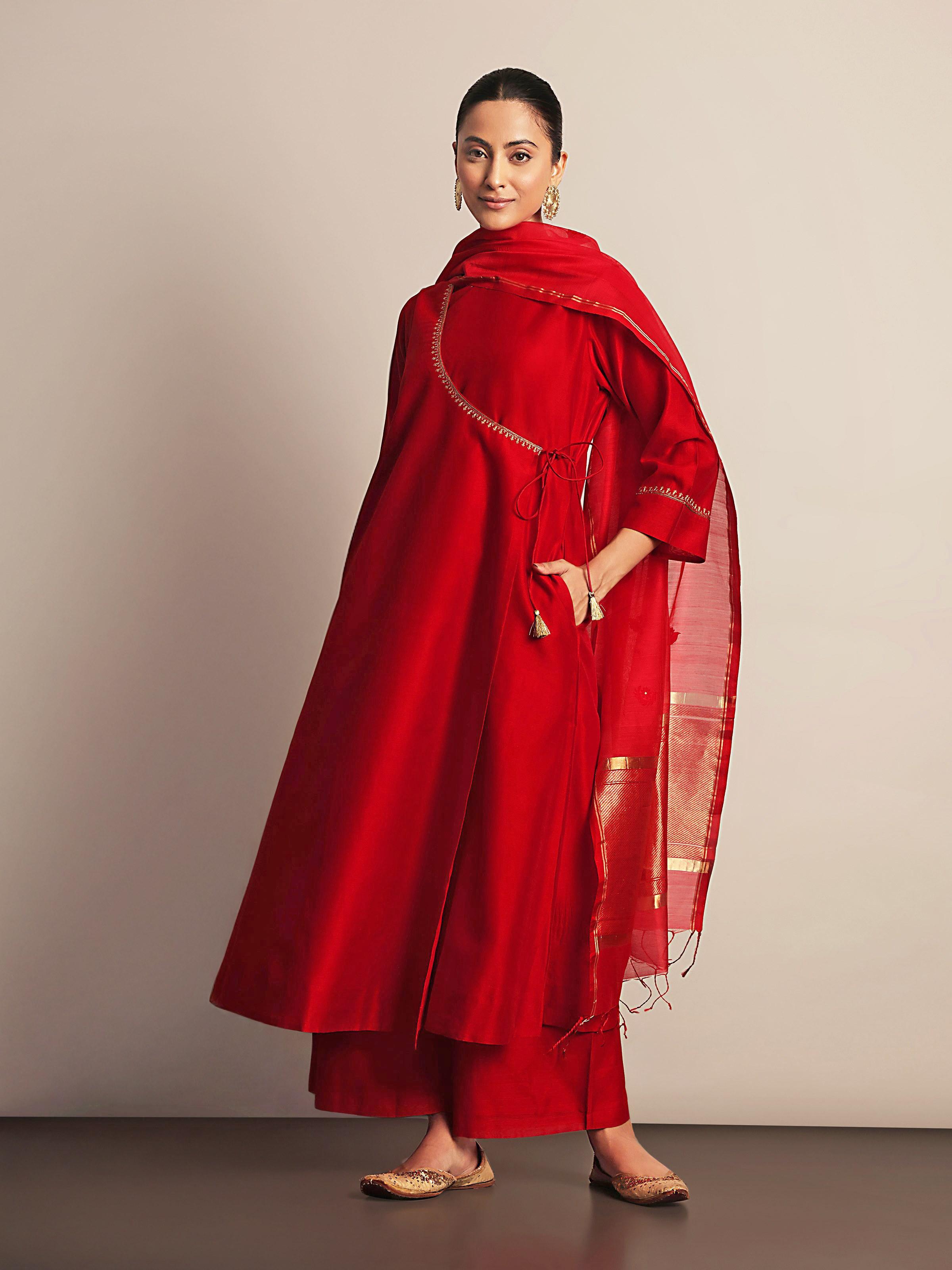 Lifestyle view of red Chanderi Angrakha kurta styled with statement earrings and churidar pants.