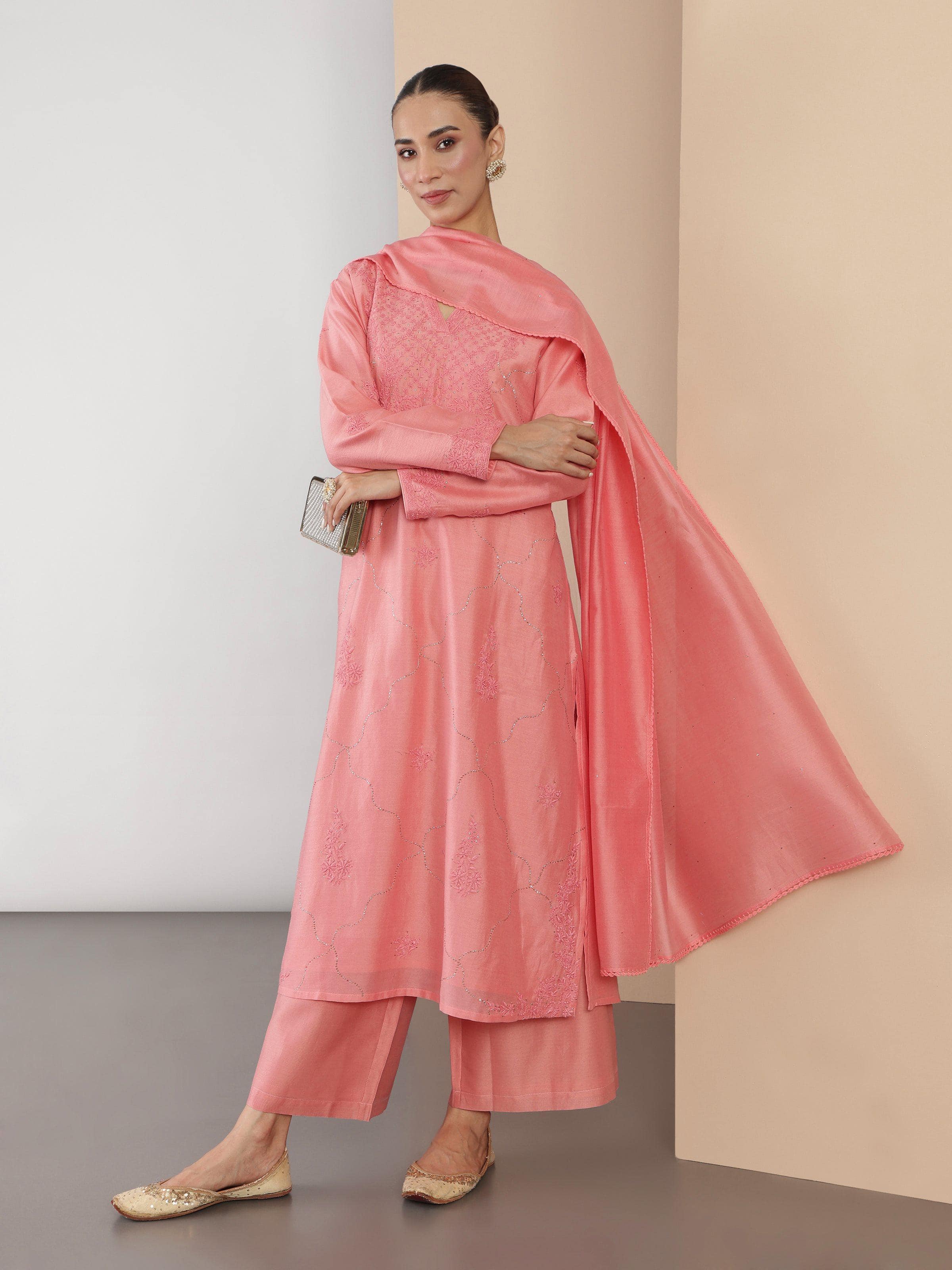 Lifestyle image of pink silk Chikankari kurta set worn with matching accessories.