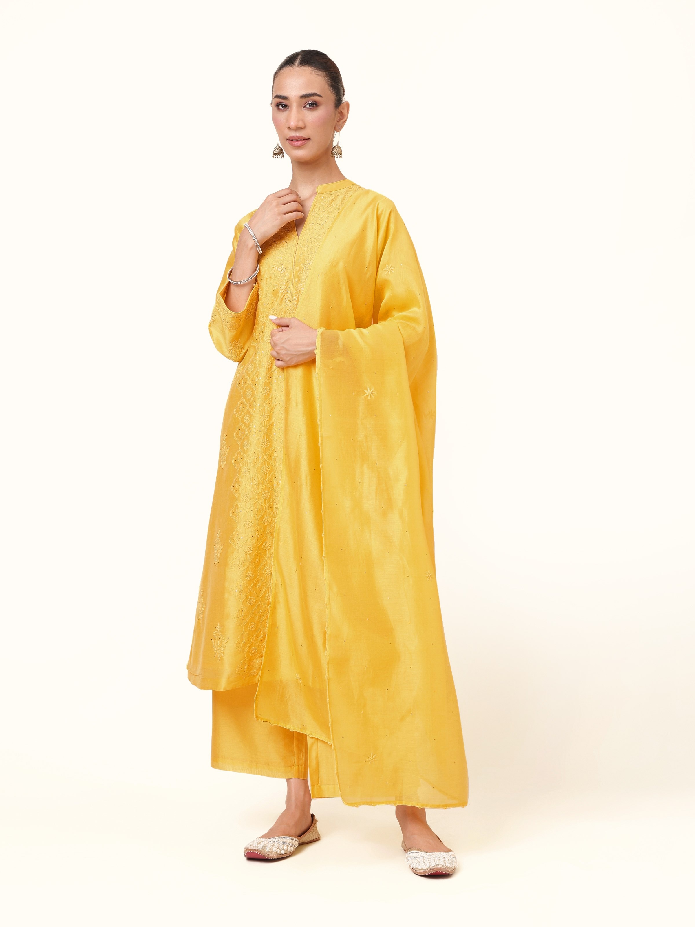Front view of yellow silk Chikankari kurta set featuring intricate embroidery, paired with matching pants and dupatta.