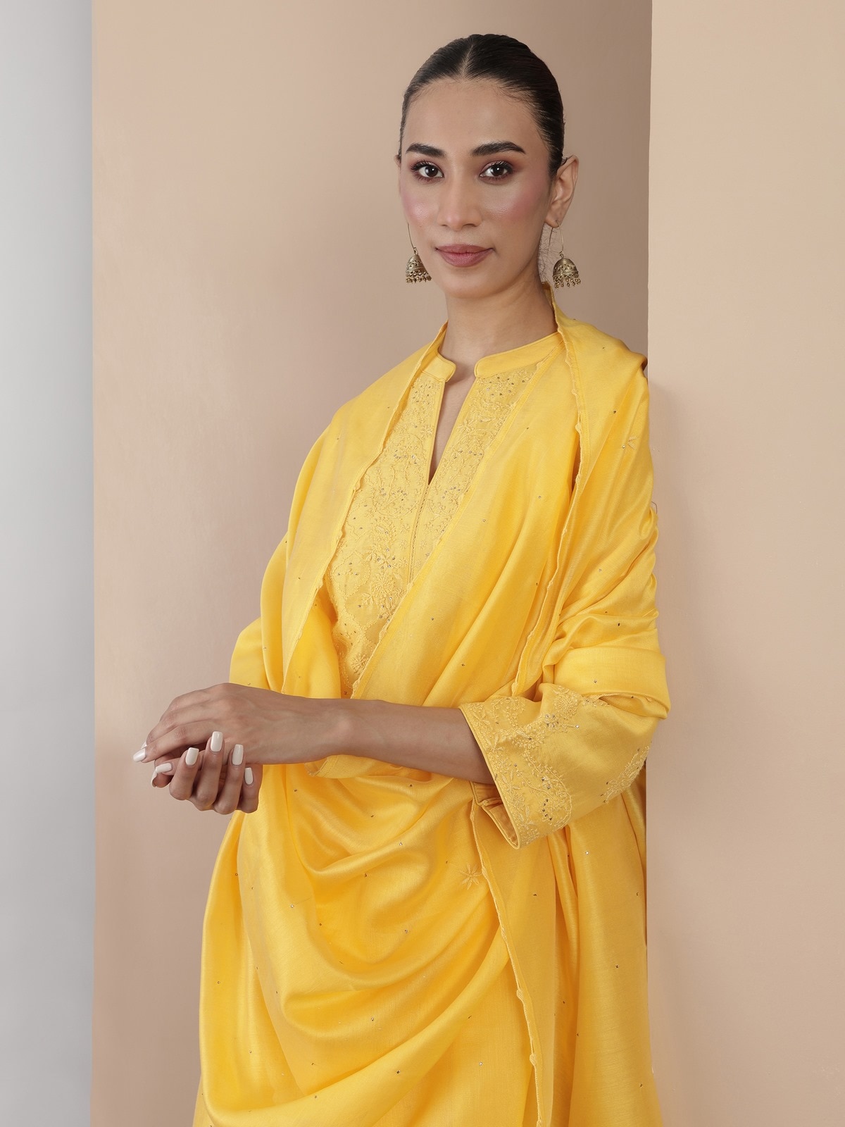 Close-up view of yellow Chikankari kurta set showing embroidered details on kurta and dupatta.