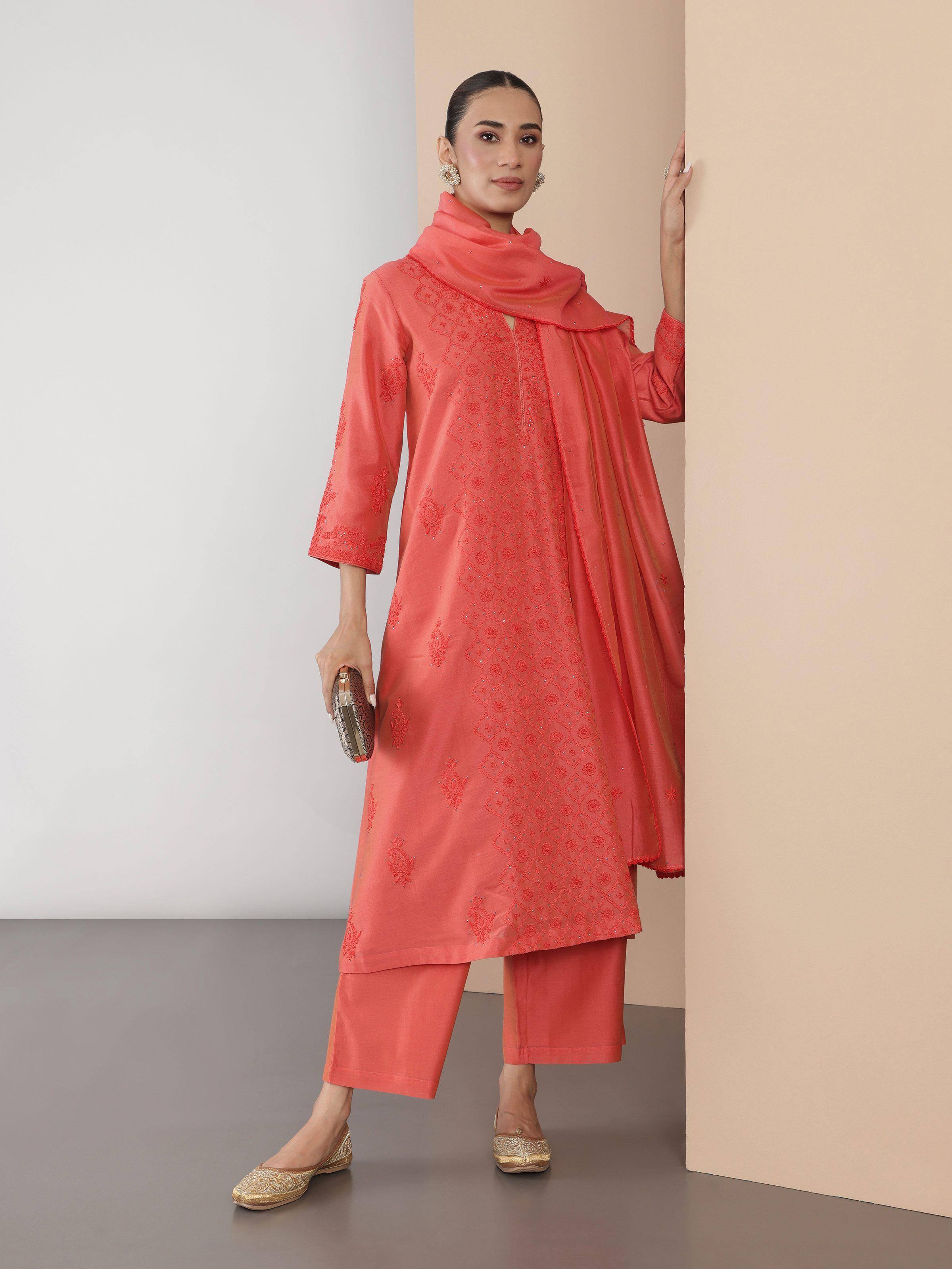 Lifestyle view of coral Chikankari silk kurta set styled with dupatta and pants.