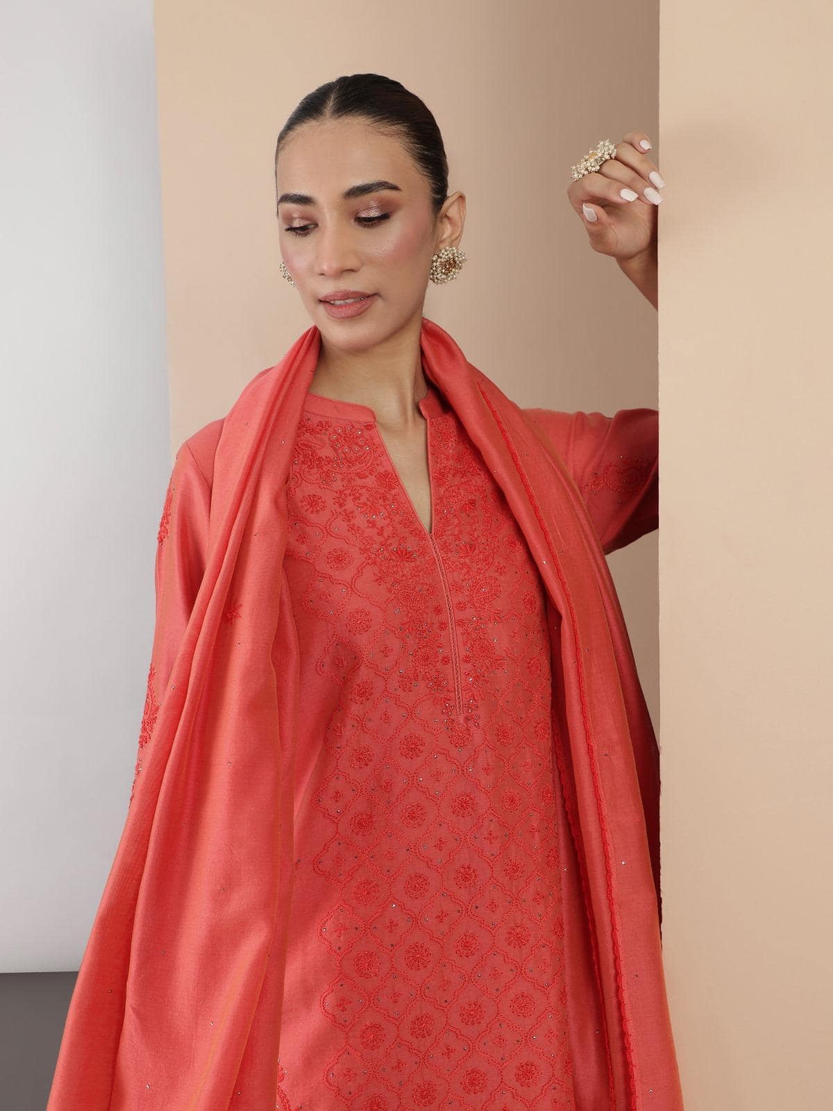 Second lifestyle view of coral orange kurta set highlighting embroidery on sleeves.
