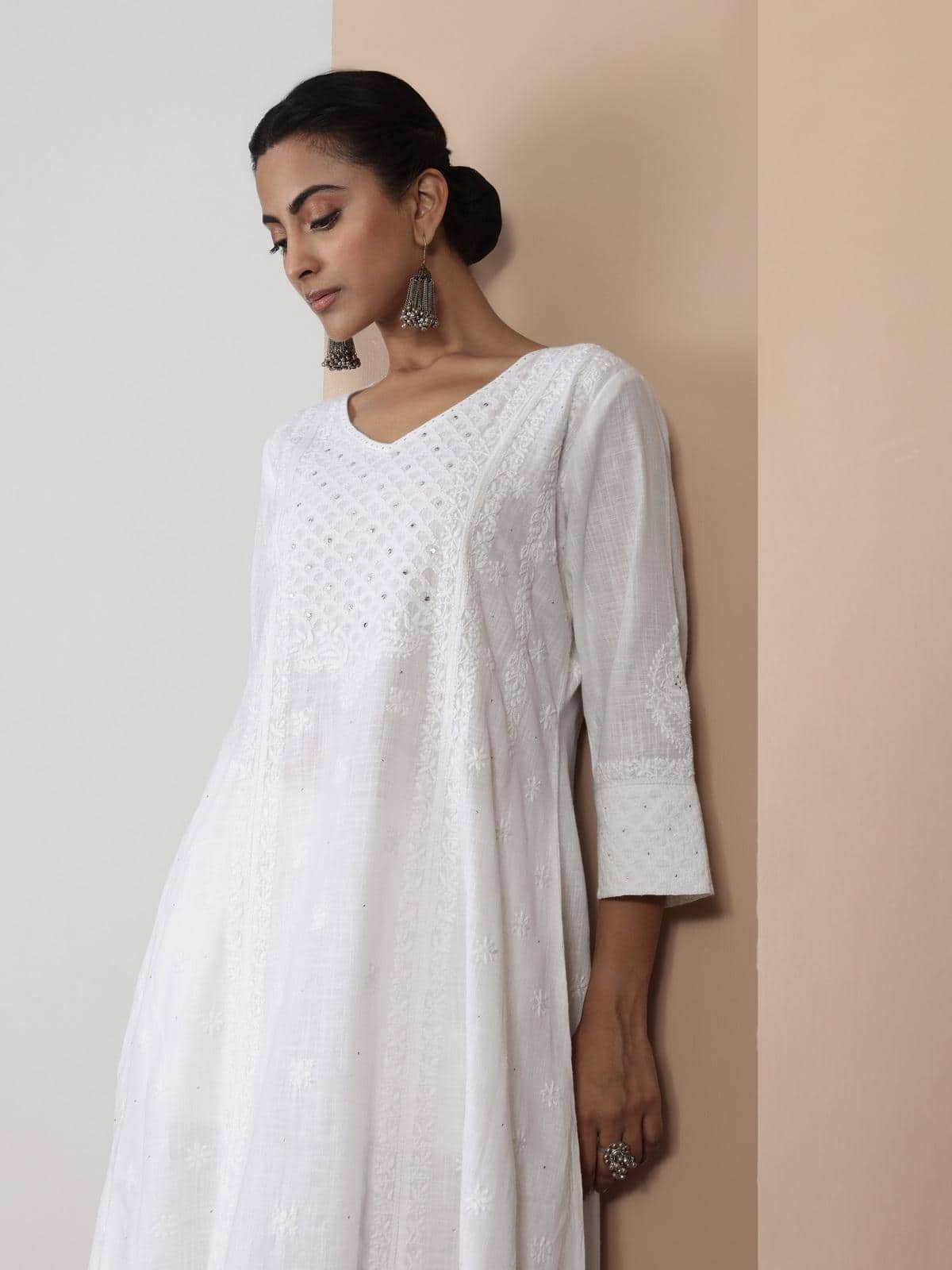 Side view of white cotton A-line kurta highlighting the fine hand embroidery and flowy fabric.