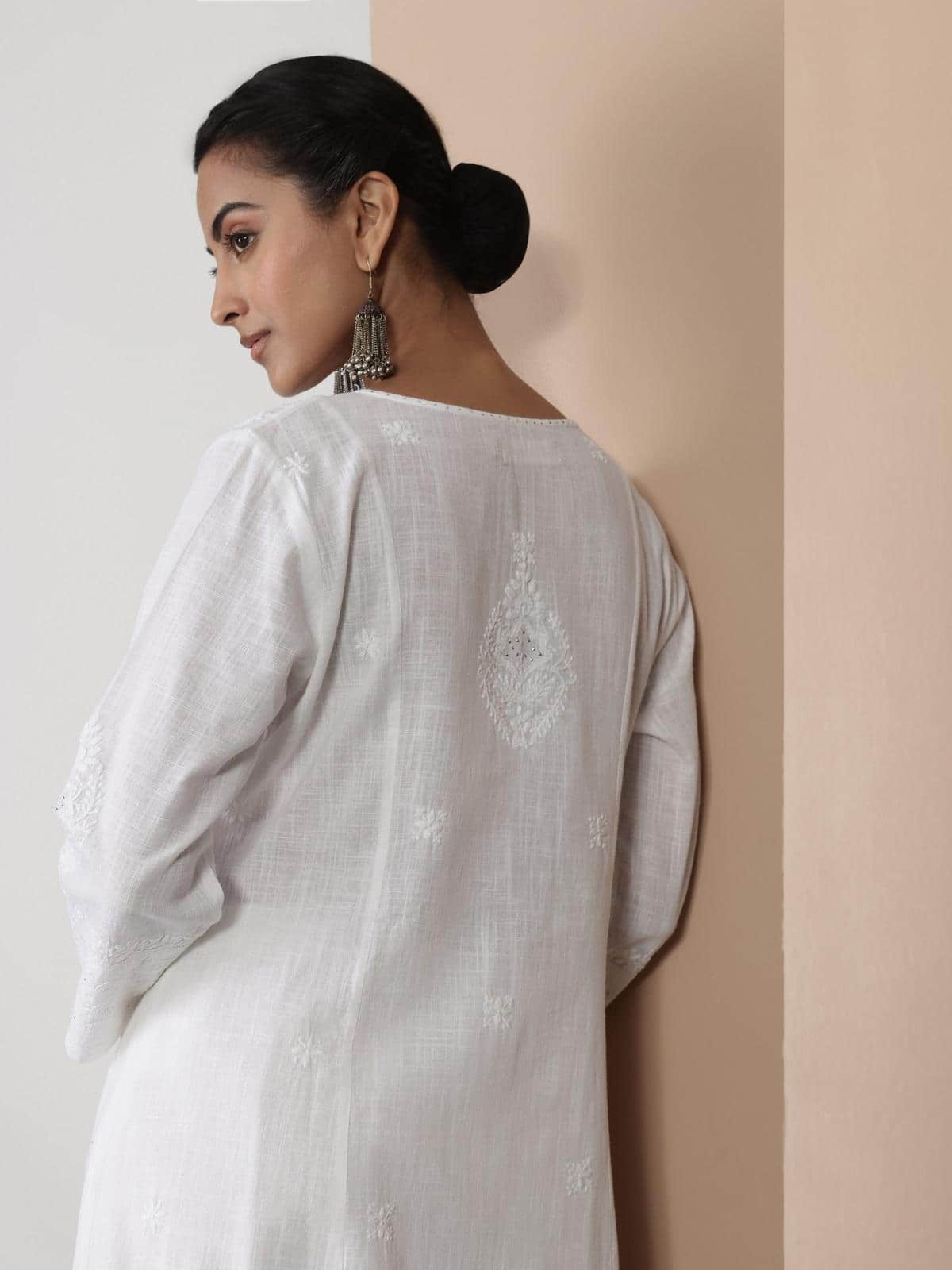 Close-up view of White Chikankari kurta worn by model with the intricate neckline and front detailing.