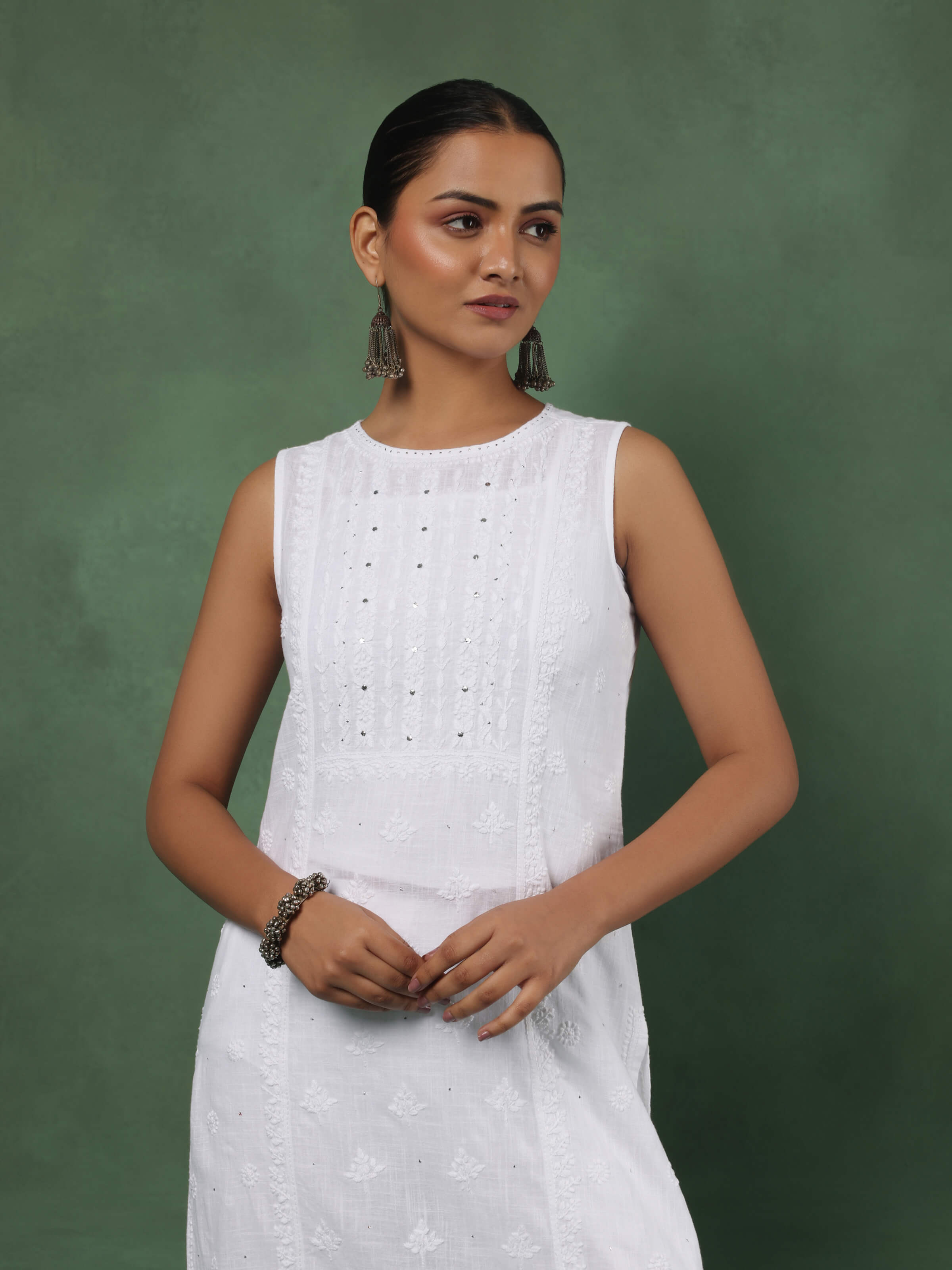 Angled view of white cotton sleeveless kurta highlighting fine Chikankari motifs and flared silhouette