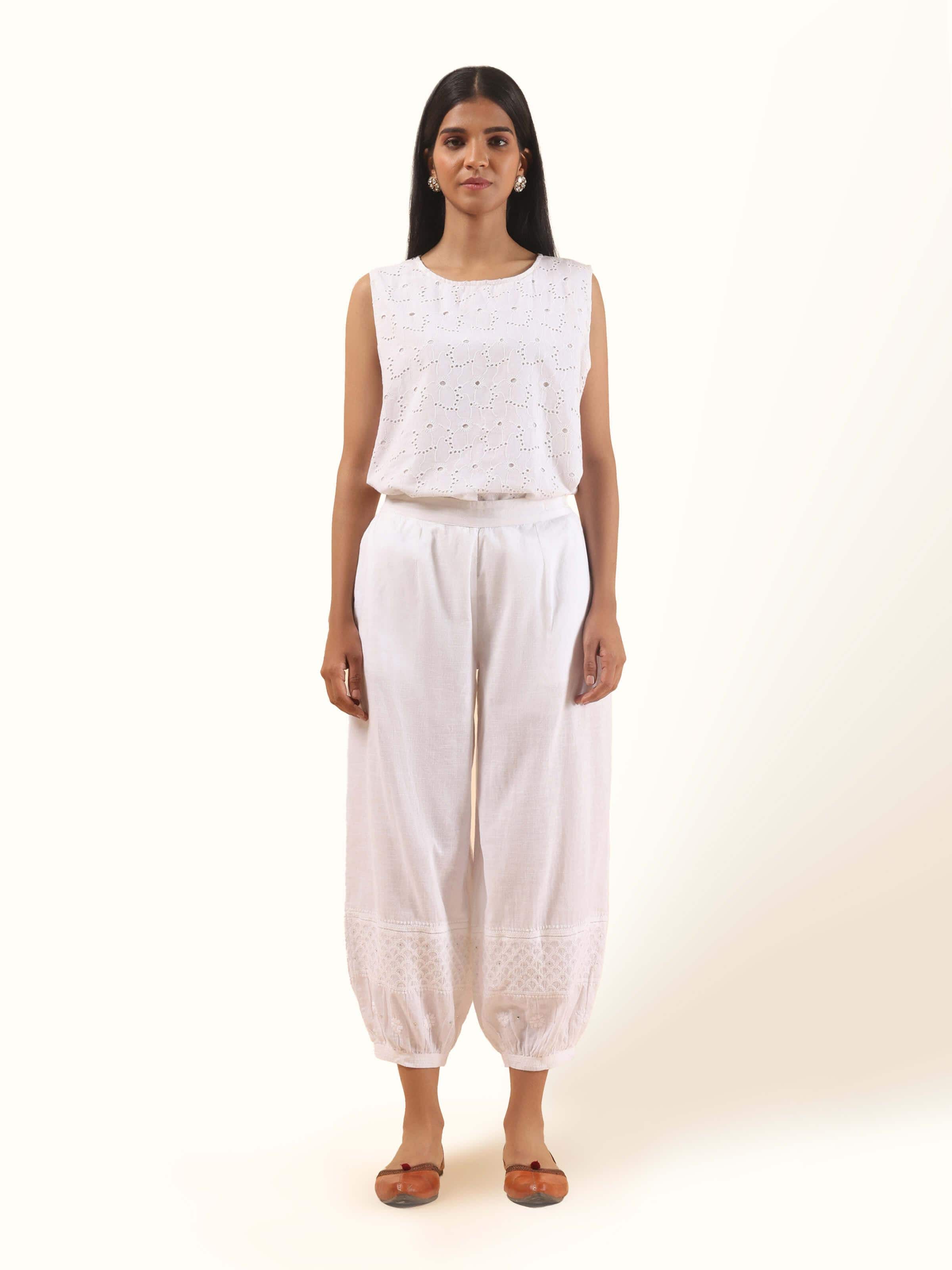 Front view of White cotton chikankari harem pants folded neatly, showcasing delicate hand-embroidered floral patterns.