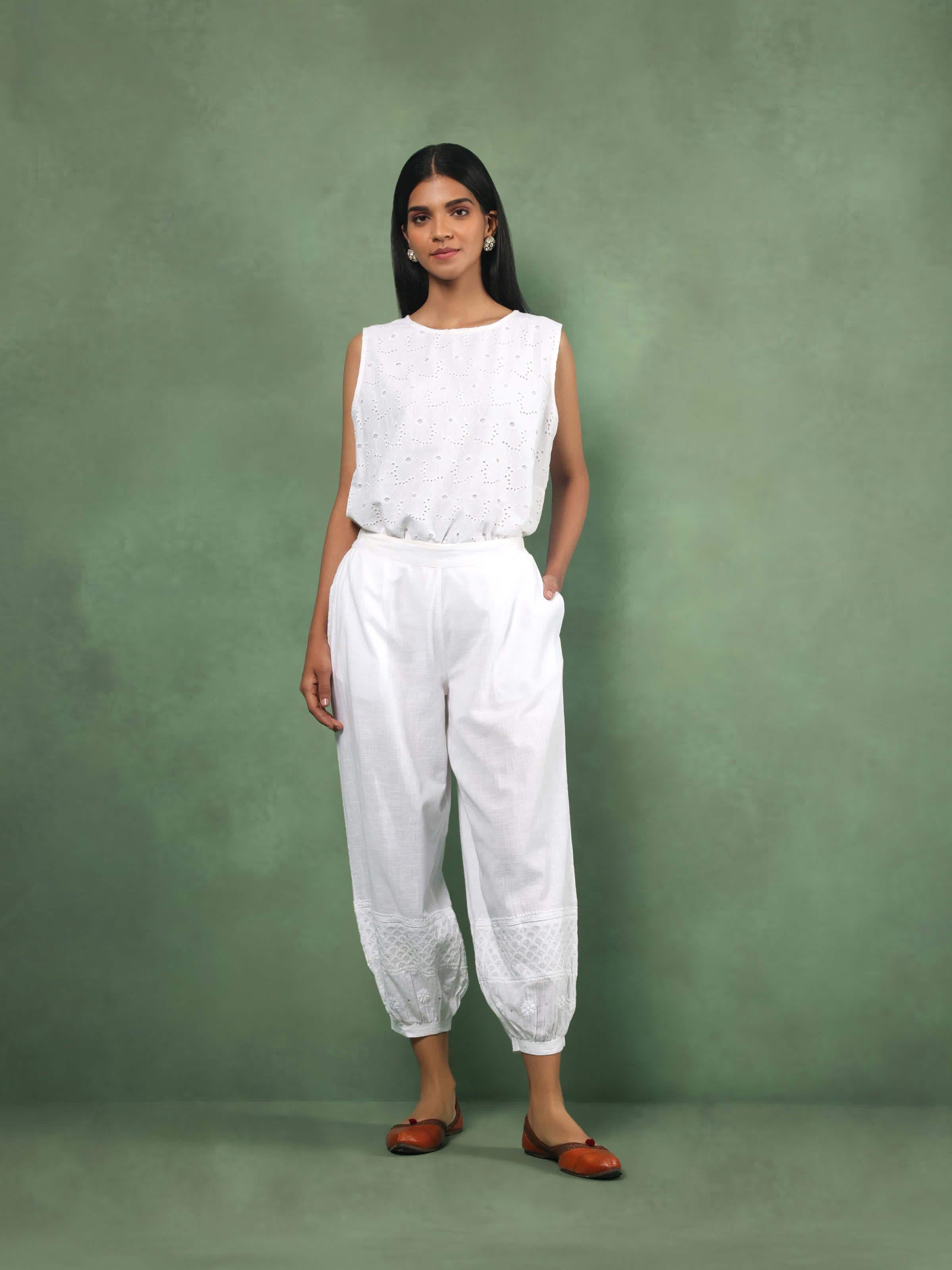 Front close-up view of intricate chikankari embroidery on white cotton fabric of harem pants highlighting fine threadwork.