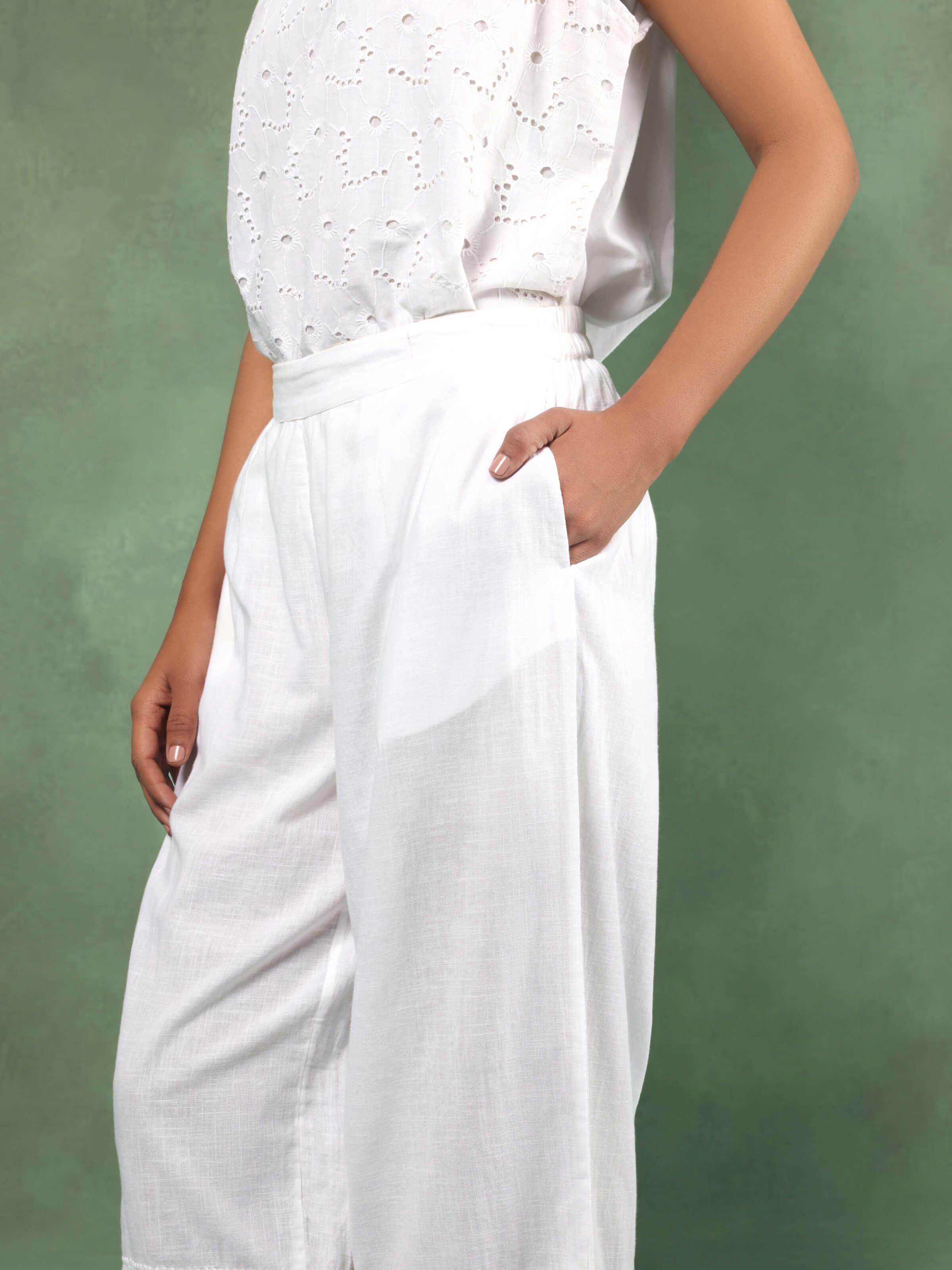 Side view of White cotton chikankari harem pants displayed flat, revealing detailed embroidery and loose, comfortable silhouette.