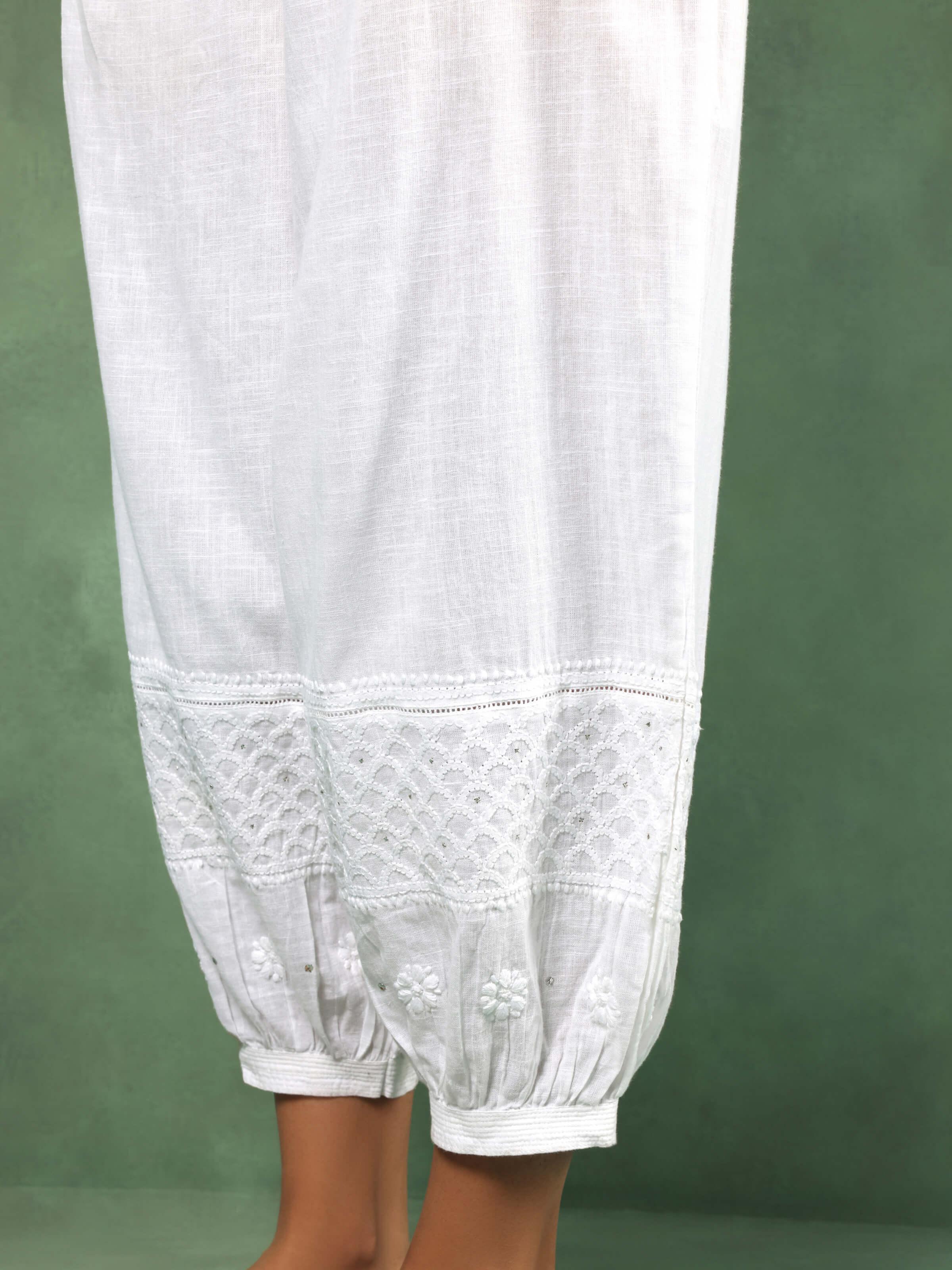 Close-up view of the embroidered cuff and waistband detailing on white cotton chikankari harem pants.