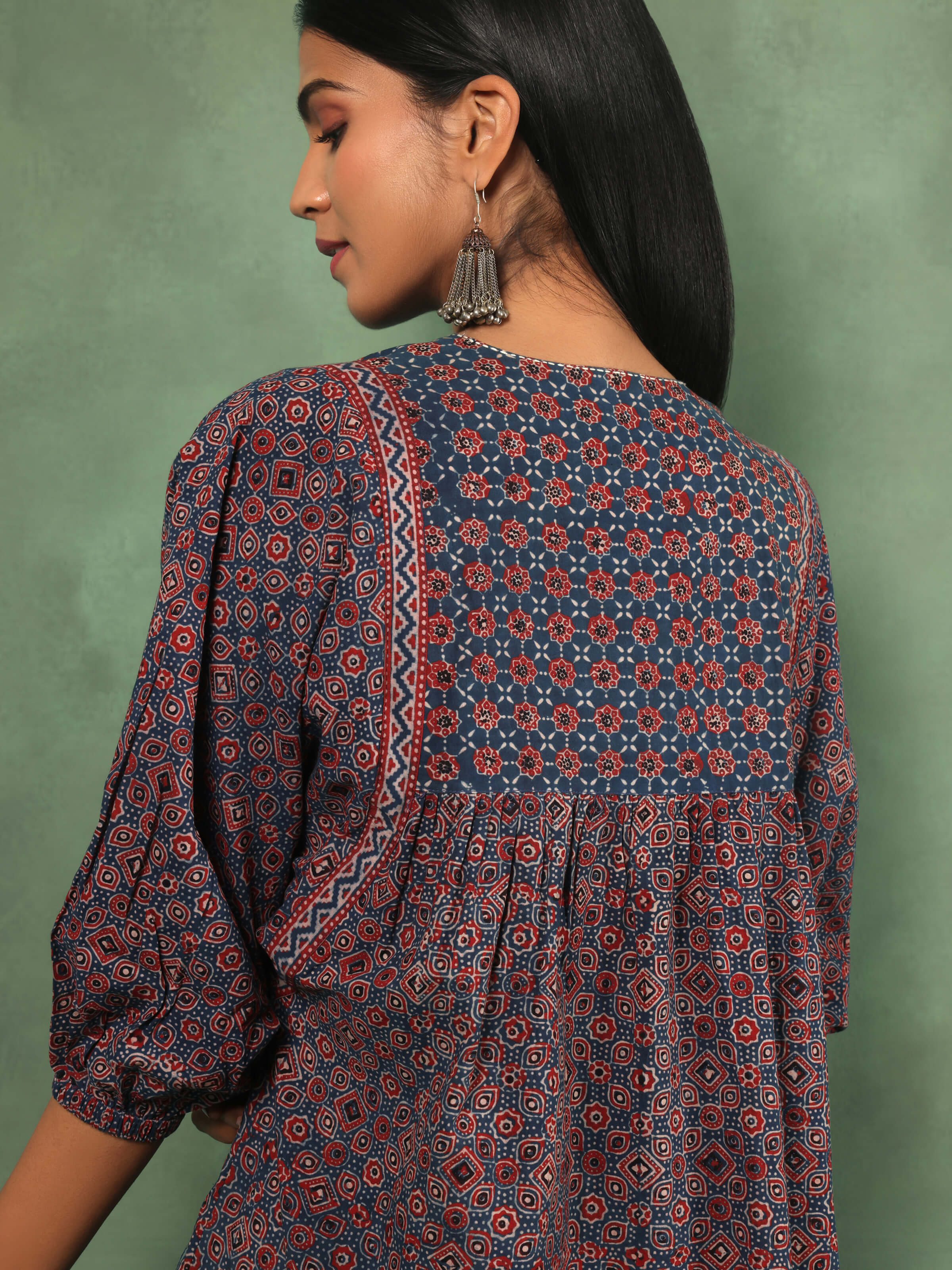 Angled view of red cotton boho top displaying side silhouette and Ajrakh pattern spread