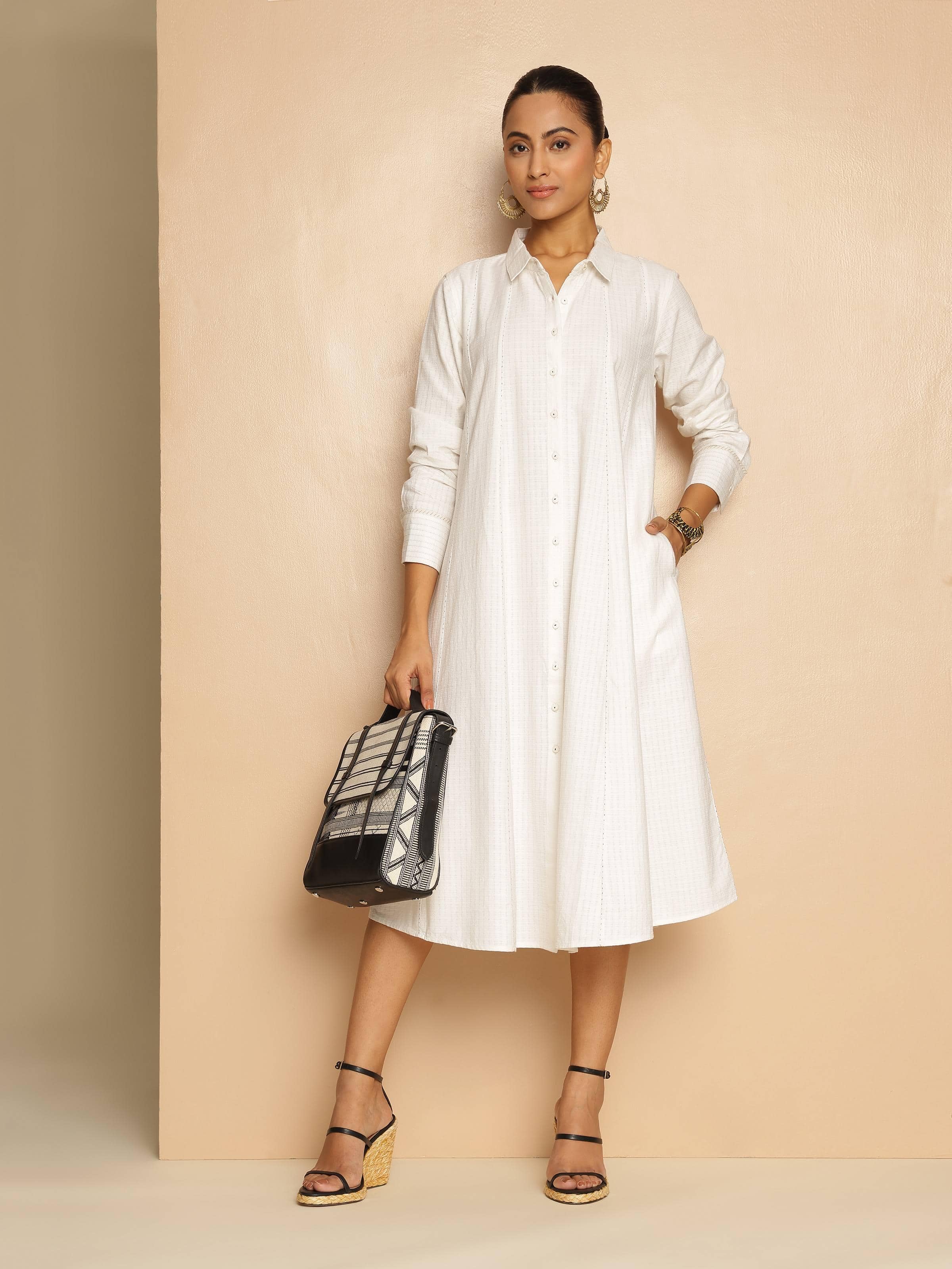 Lifestyle view of off-white cotton panelled straight dress styled with minimal accessories