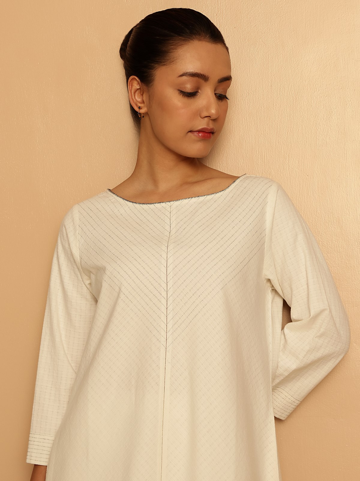Angled lifestyle view of off-white cotton kurta showing relaxed sleeves
