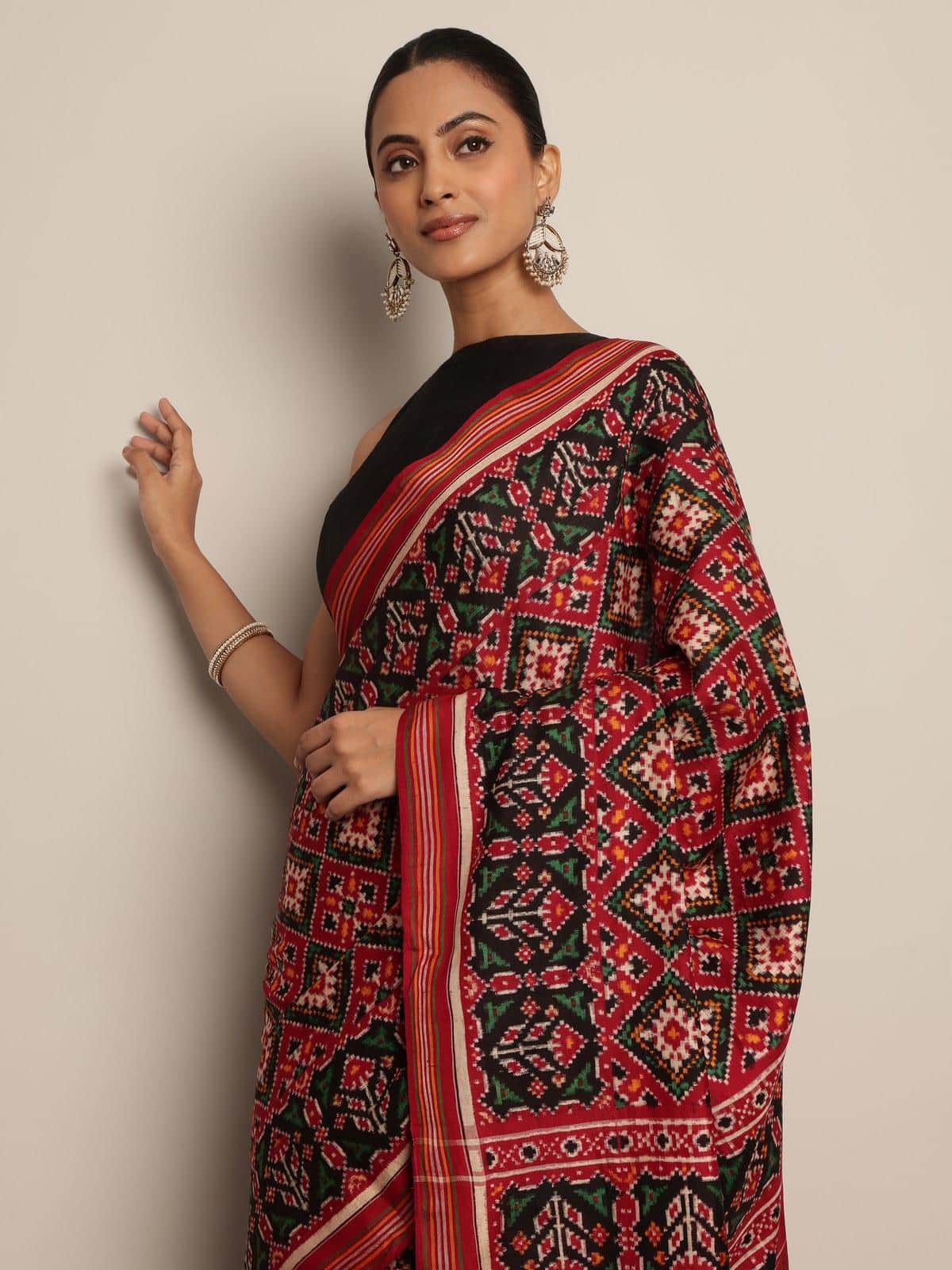 Angled view of Red & Green Mulberry Silk Patan Patola Saree highlighting intricate Patola weave and color contrast.