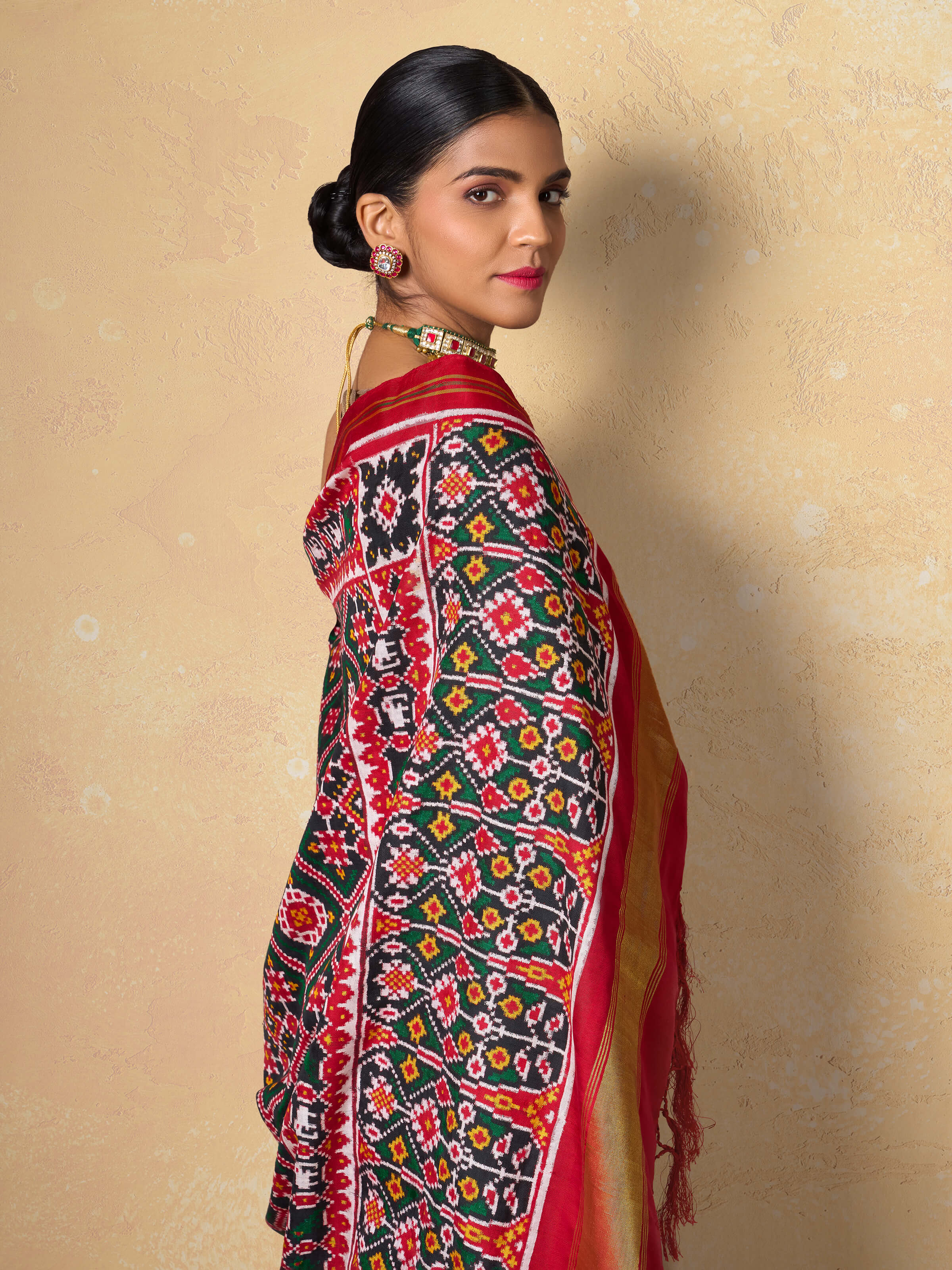 Red mulberry silk Patan Patola saree angled view emphasizing intricate double ikat weaving and rich texture