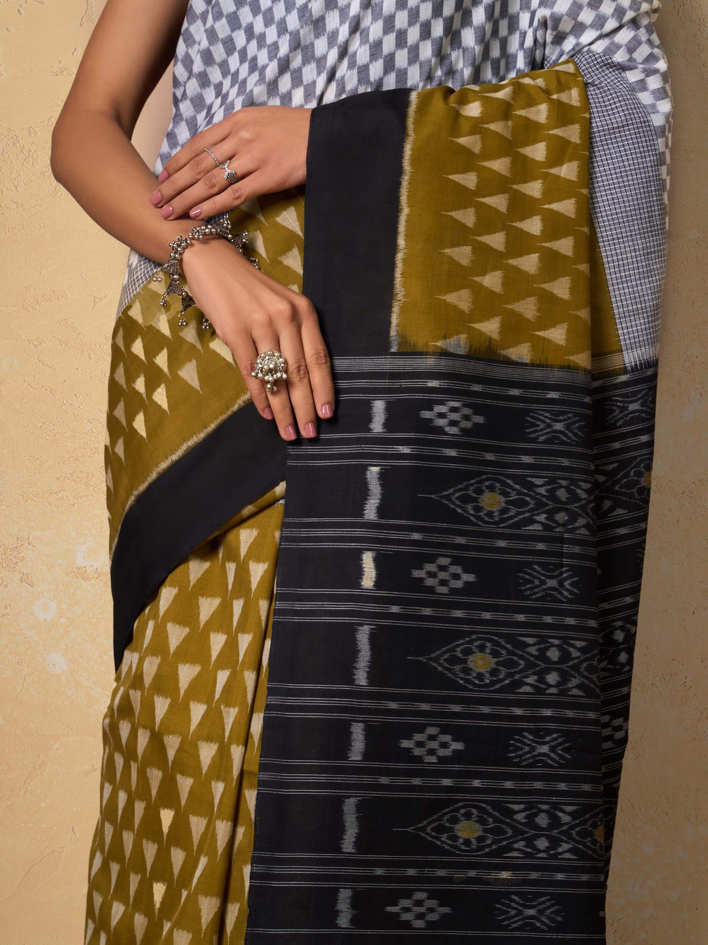 Close-up detail of handwoven ikat patterns on mustard cotton saree