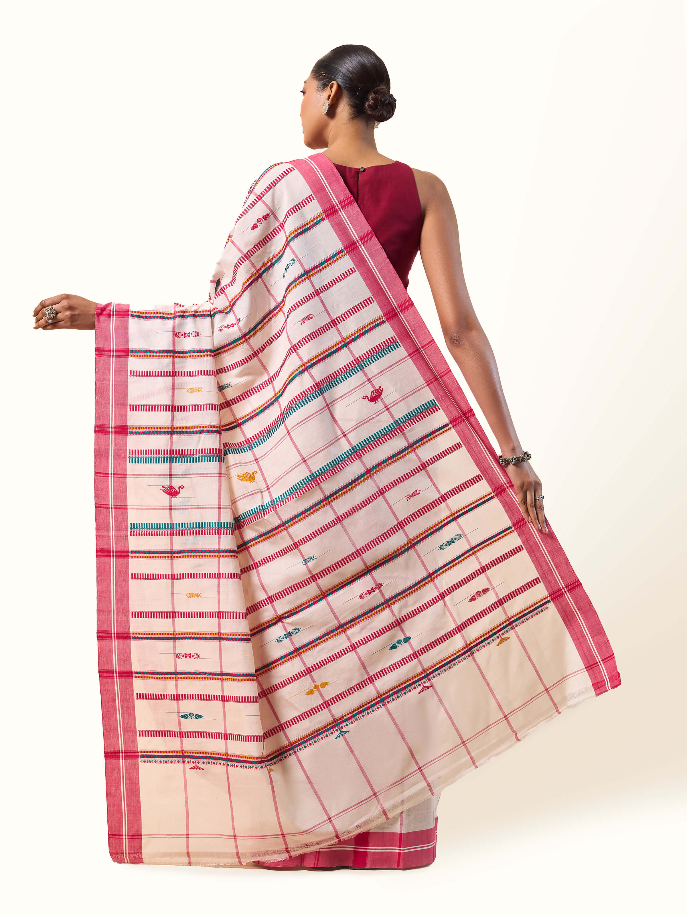 Back view of model wearing red cotton saree with traditional extra-weft weaving and elegant pleats.