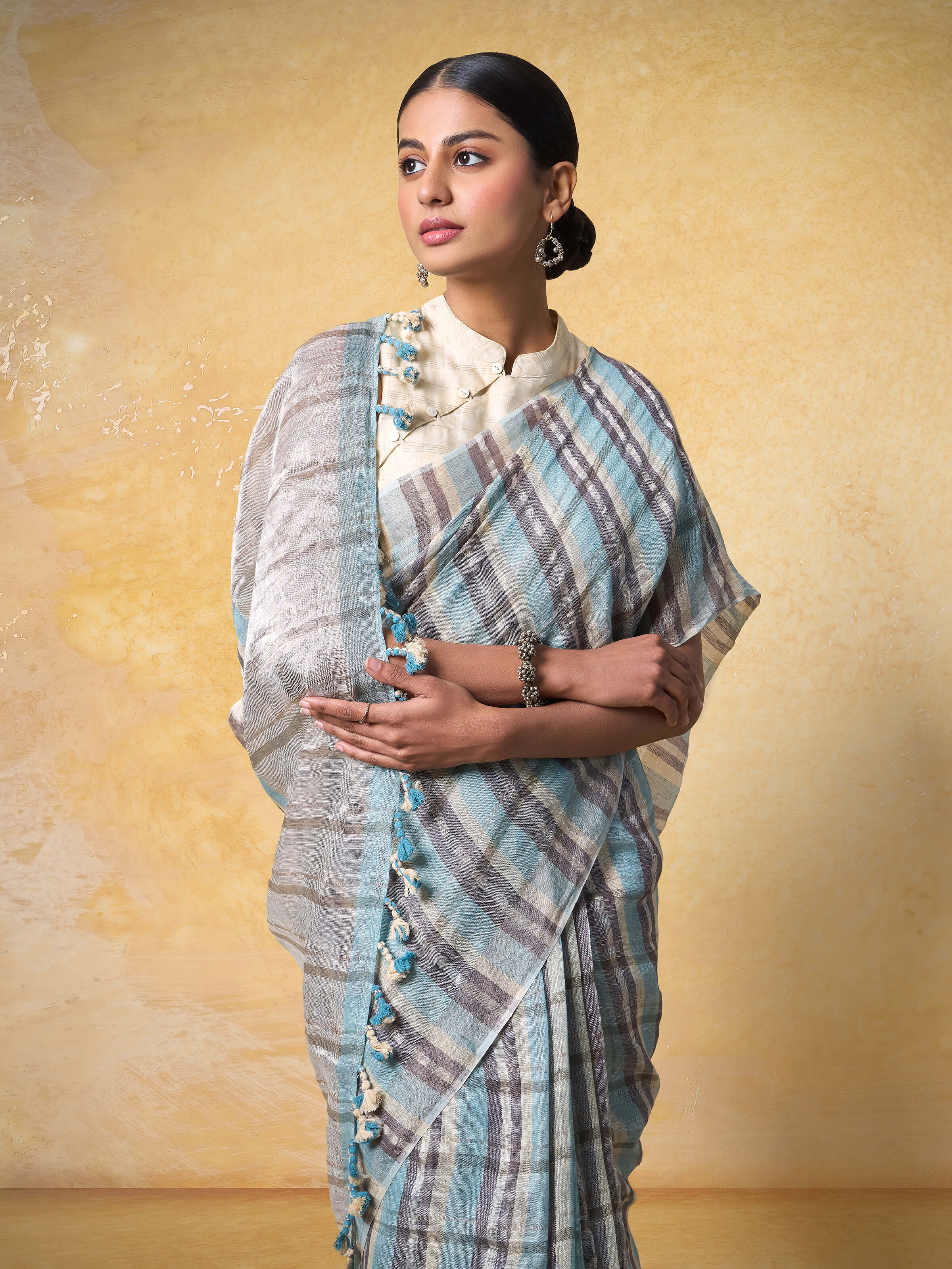 Side profile of model in grey linen saree capturing the drape and zari border in motion.