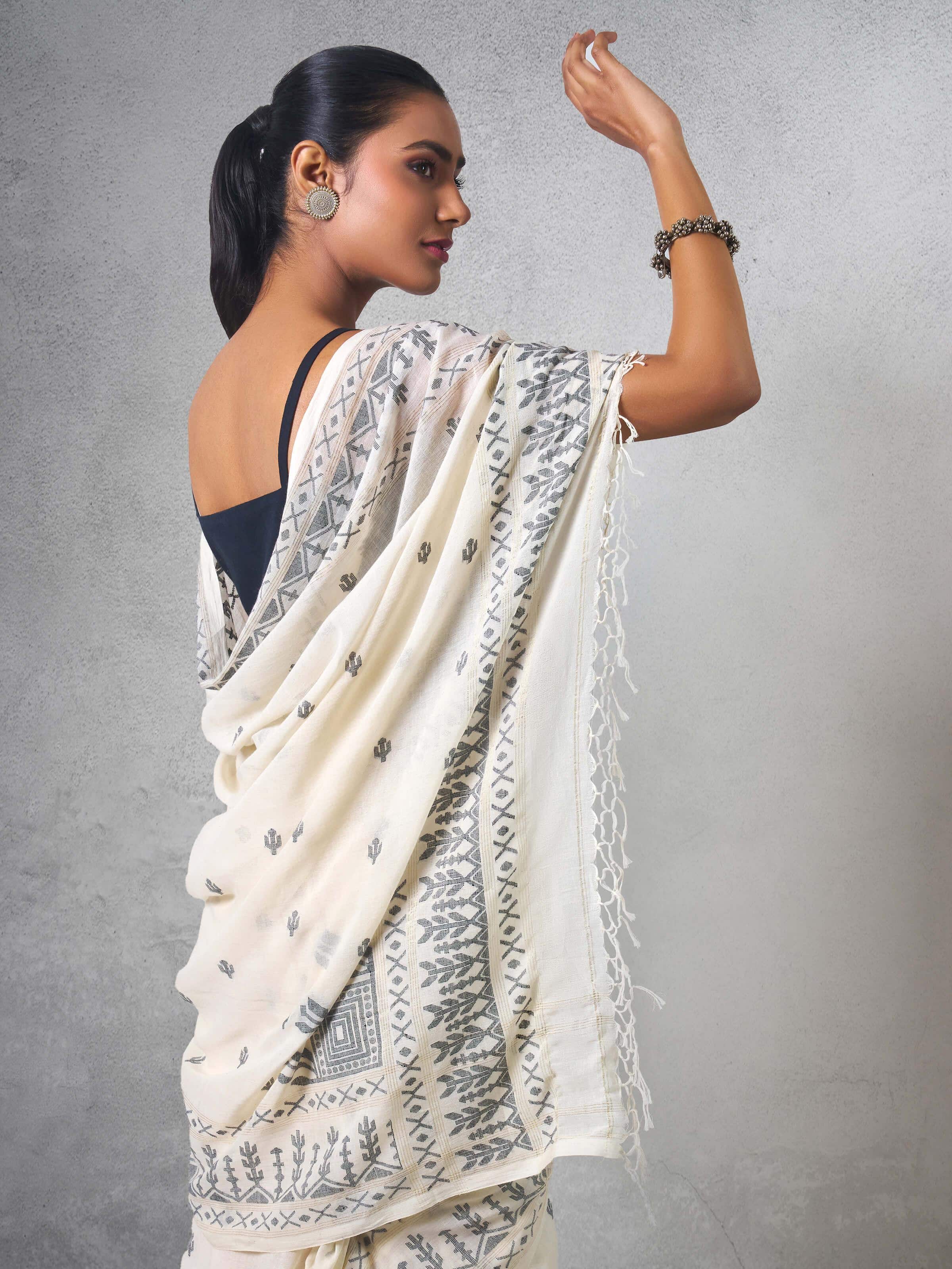 Angled view of off-white cotton Jamdani saree showing border and pallu details.