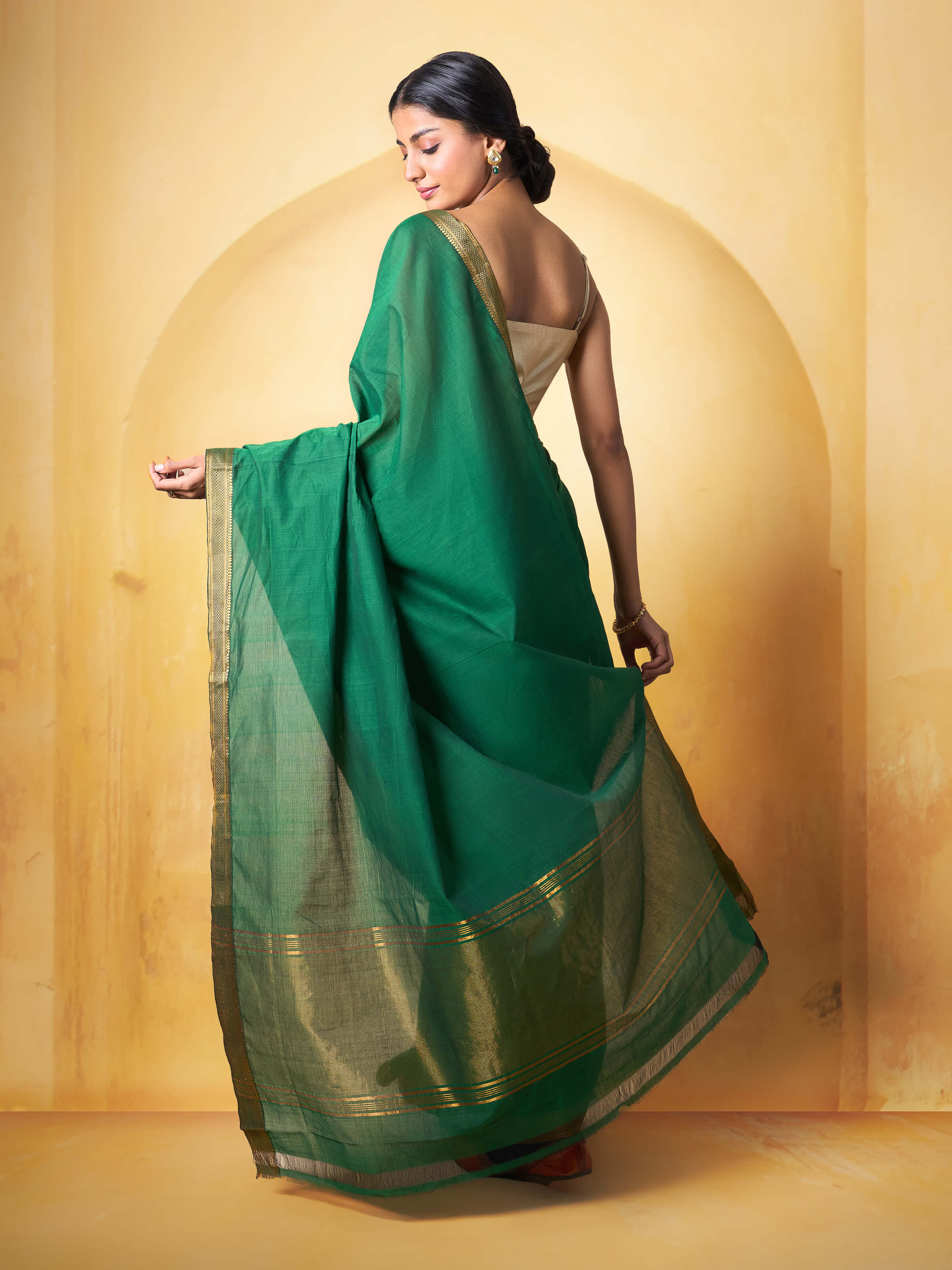 Angled view of dark green cotton Mangalgiri saree emphasizing fine weave and subtle patterns.