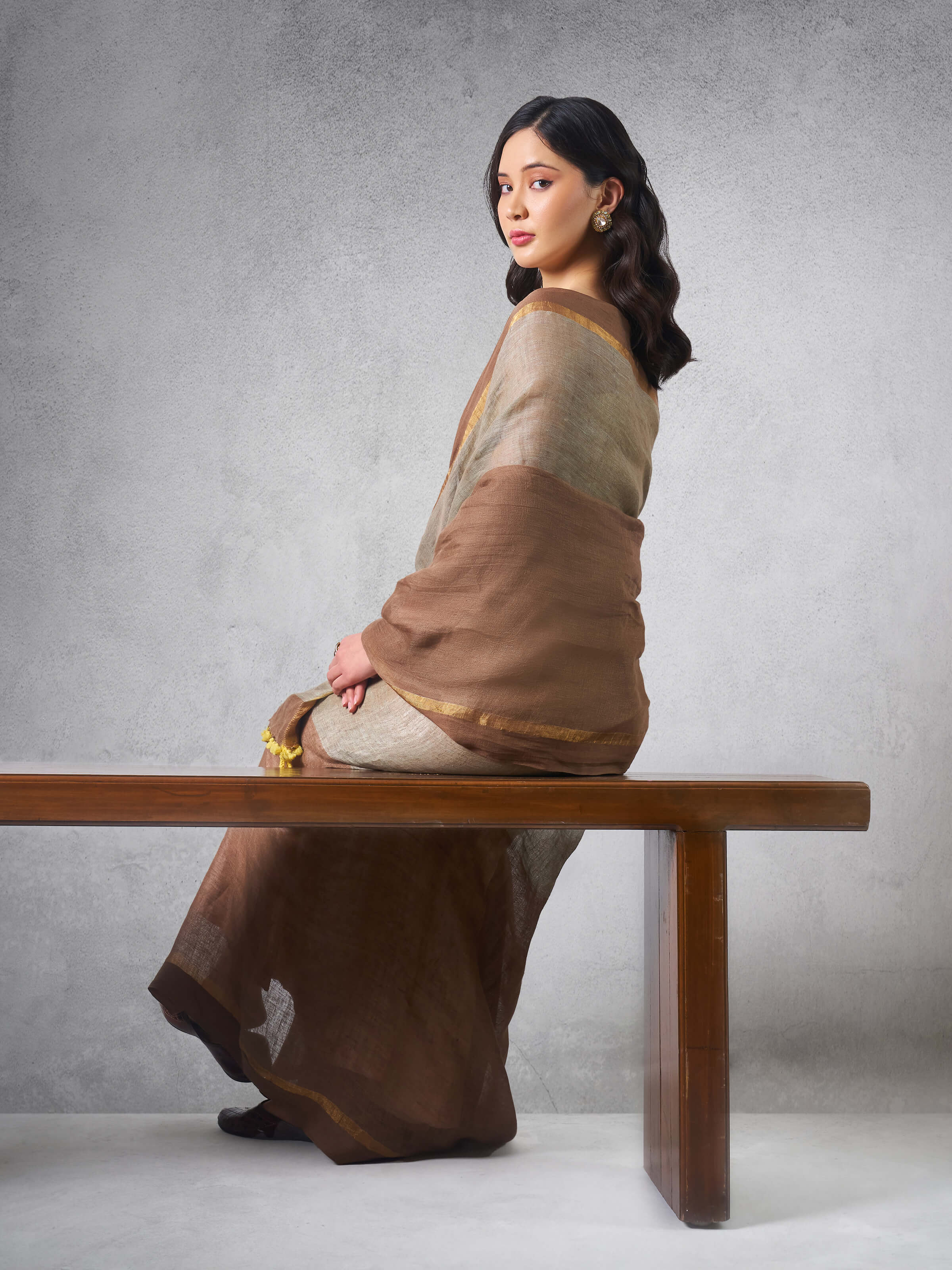 Angled view of beige linen cotton saree showing fabric drape and texture.