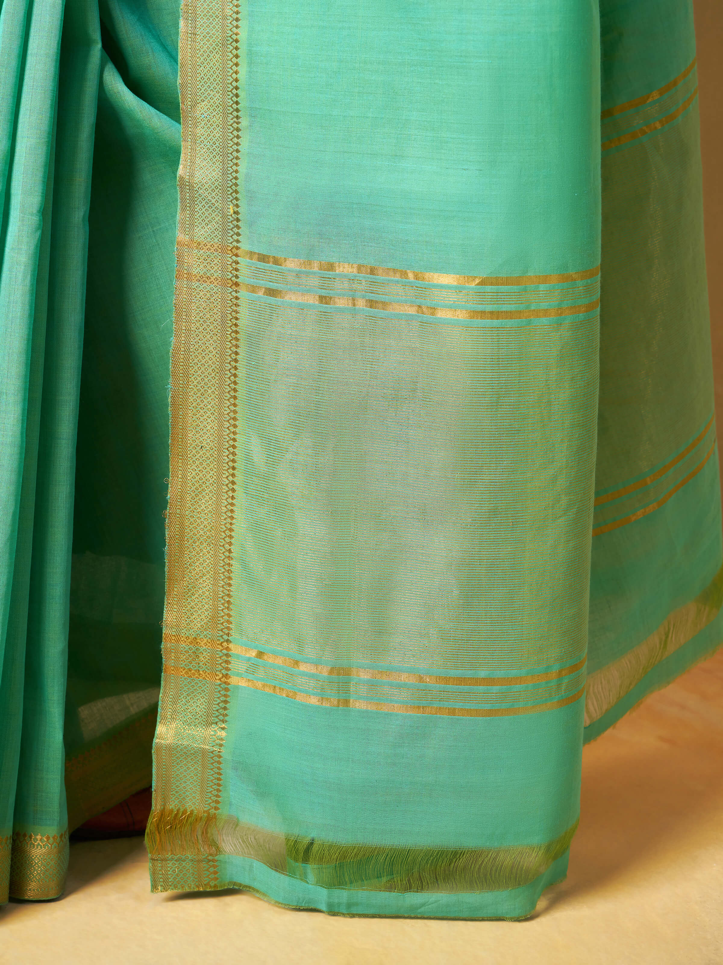 Close-up focusing on the intricate zari weaving and crisp cotton texture.