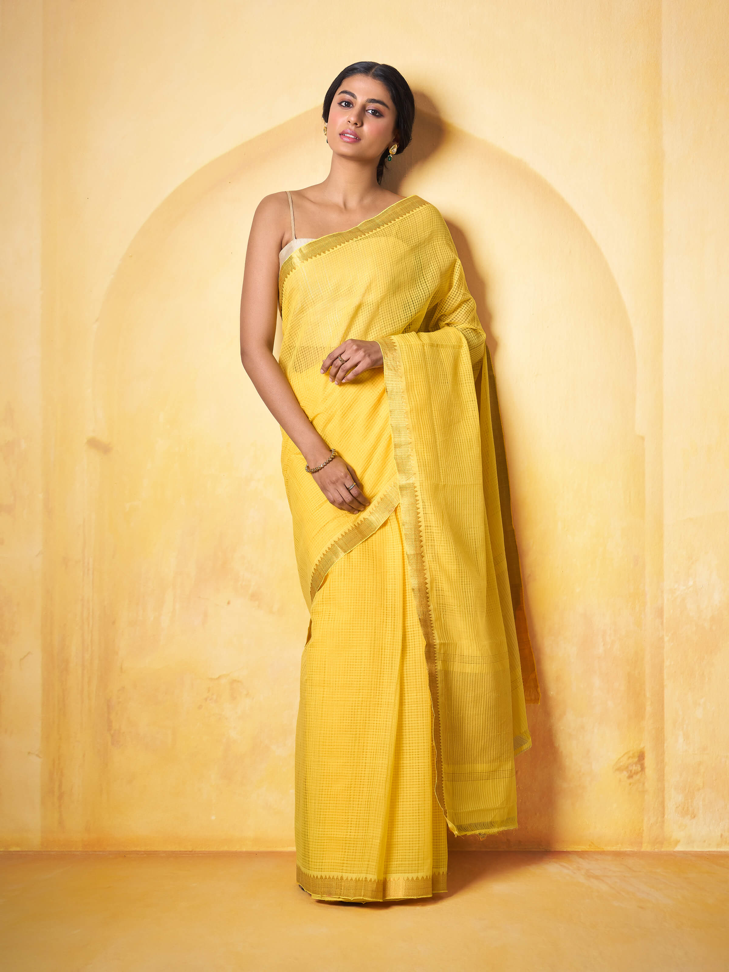 Lifestyle image of yellow and gold Mangalgiri saree styled with blouse and accessories.