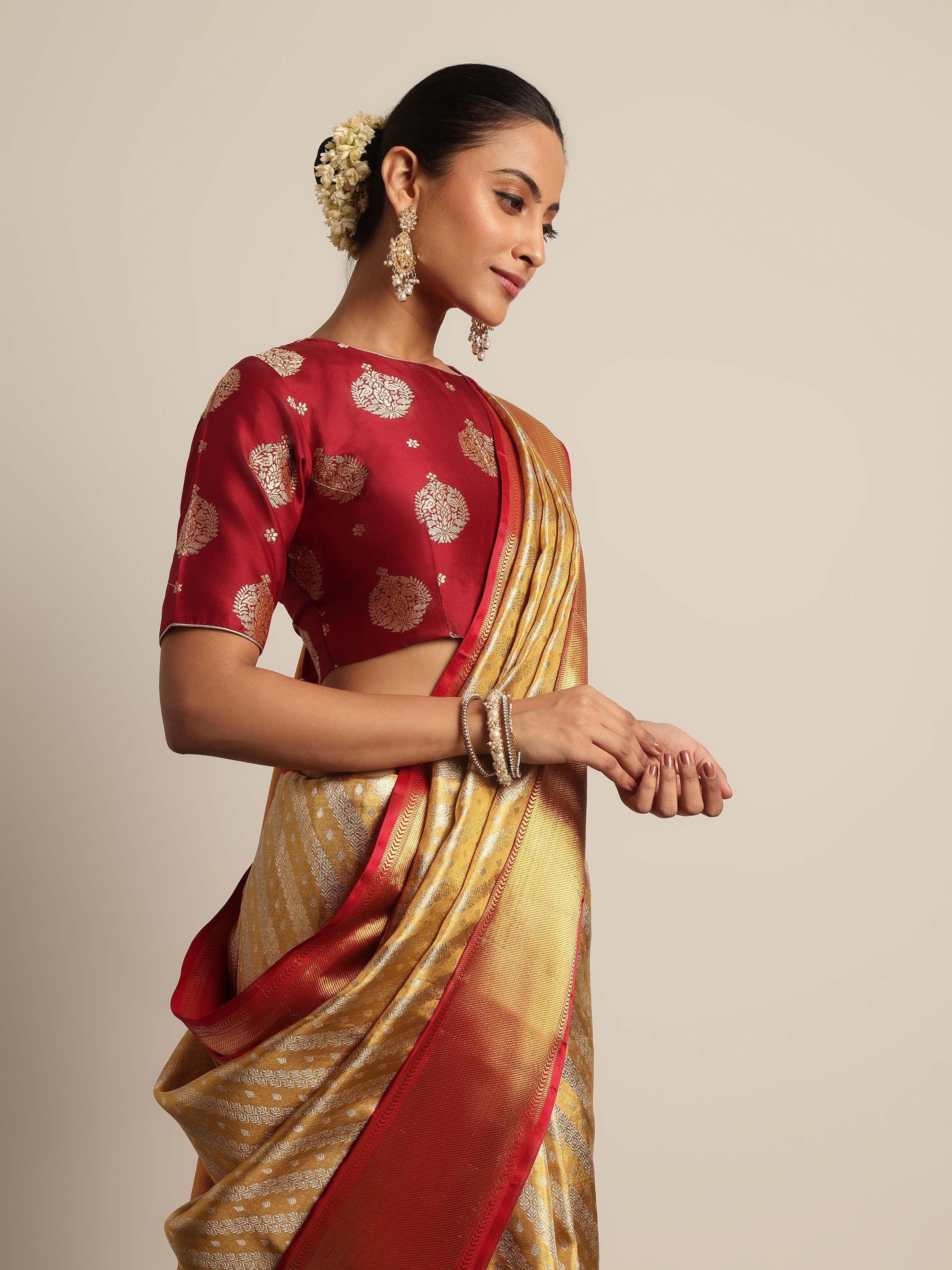 Posed view showcasing golden saree’s pleats and traditional accessories.