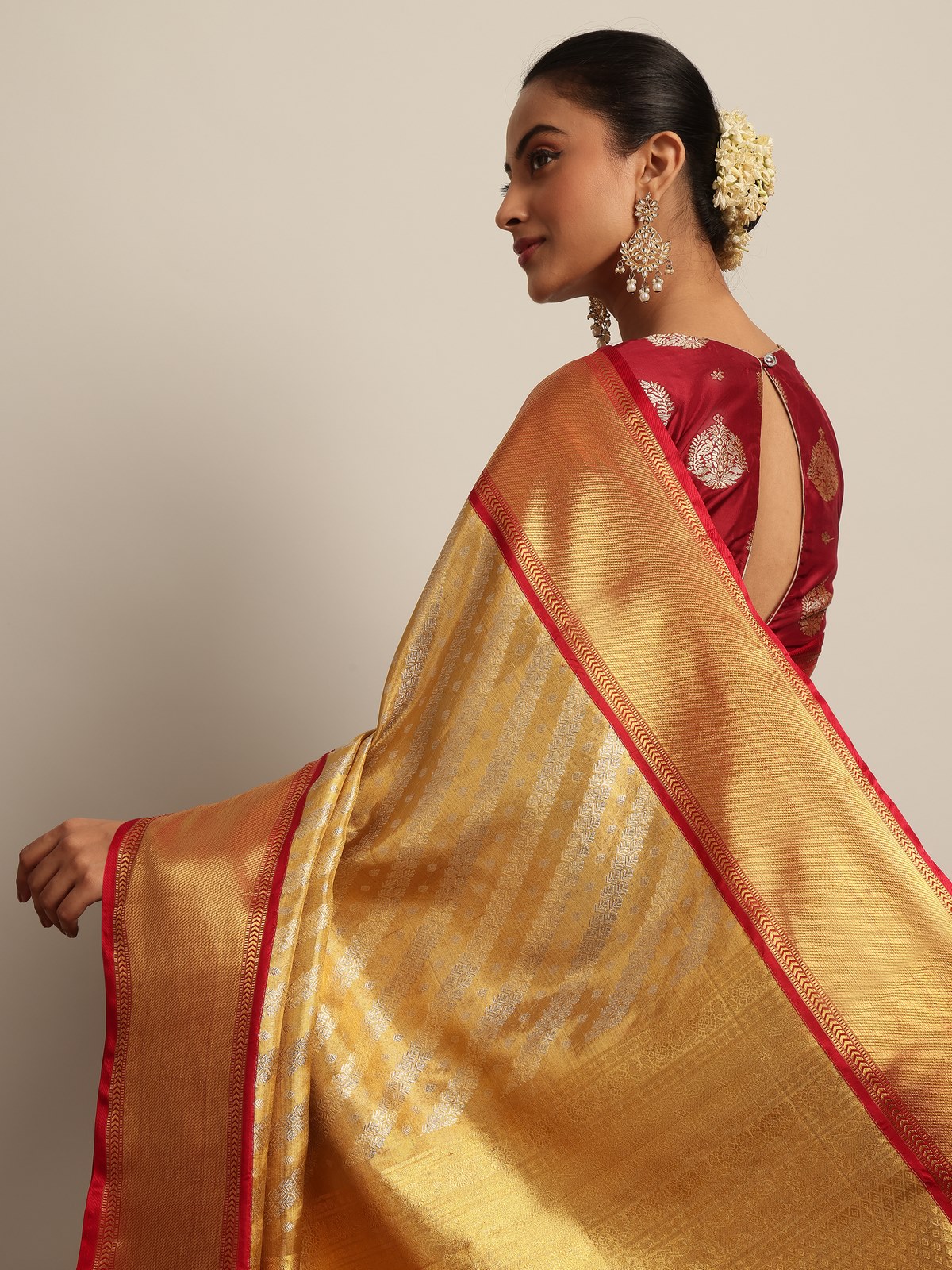 Full-length shot of model in gold Kancheepuram saree during festive moment.