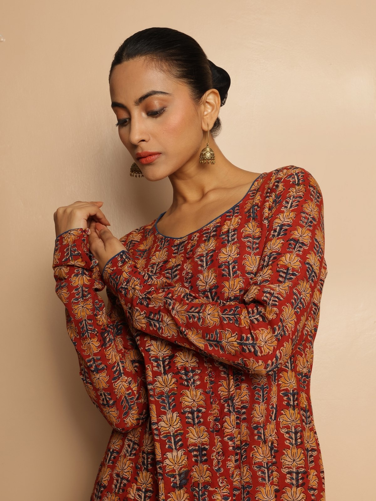 Side lifestyle image of red cotton Kalamkari kurta showing sleeve and hem styling