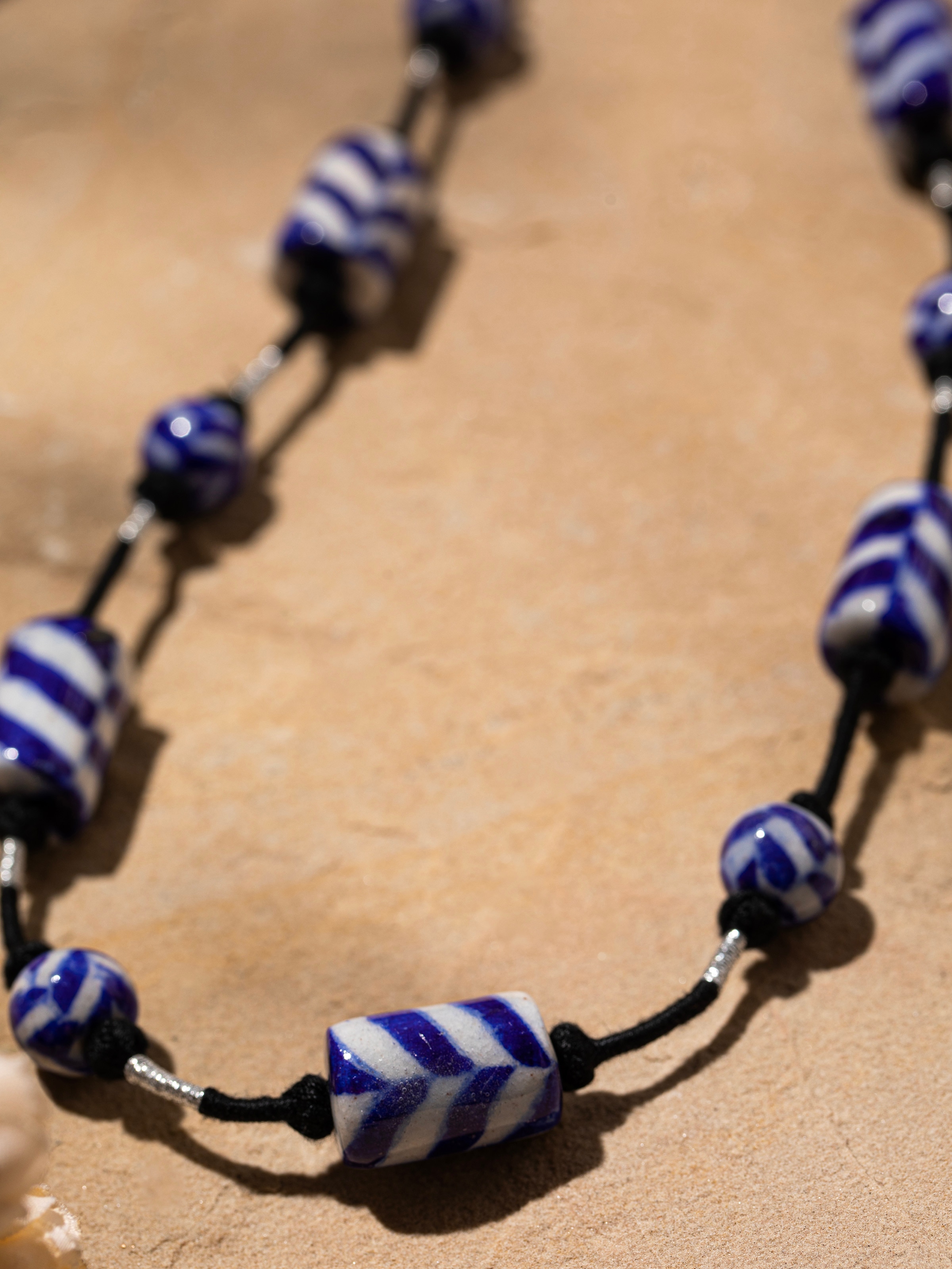 Detailed close-up of blue pottery long necklace showcasing the unique pottery designs and colors.