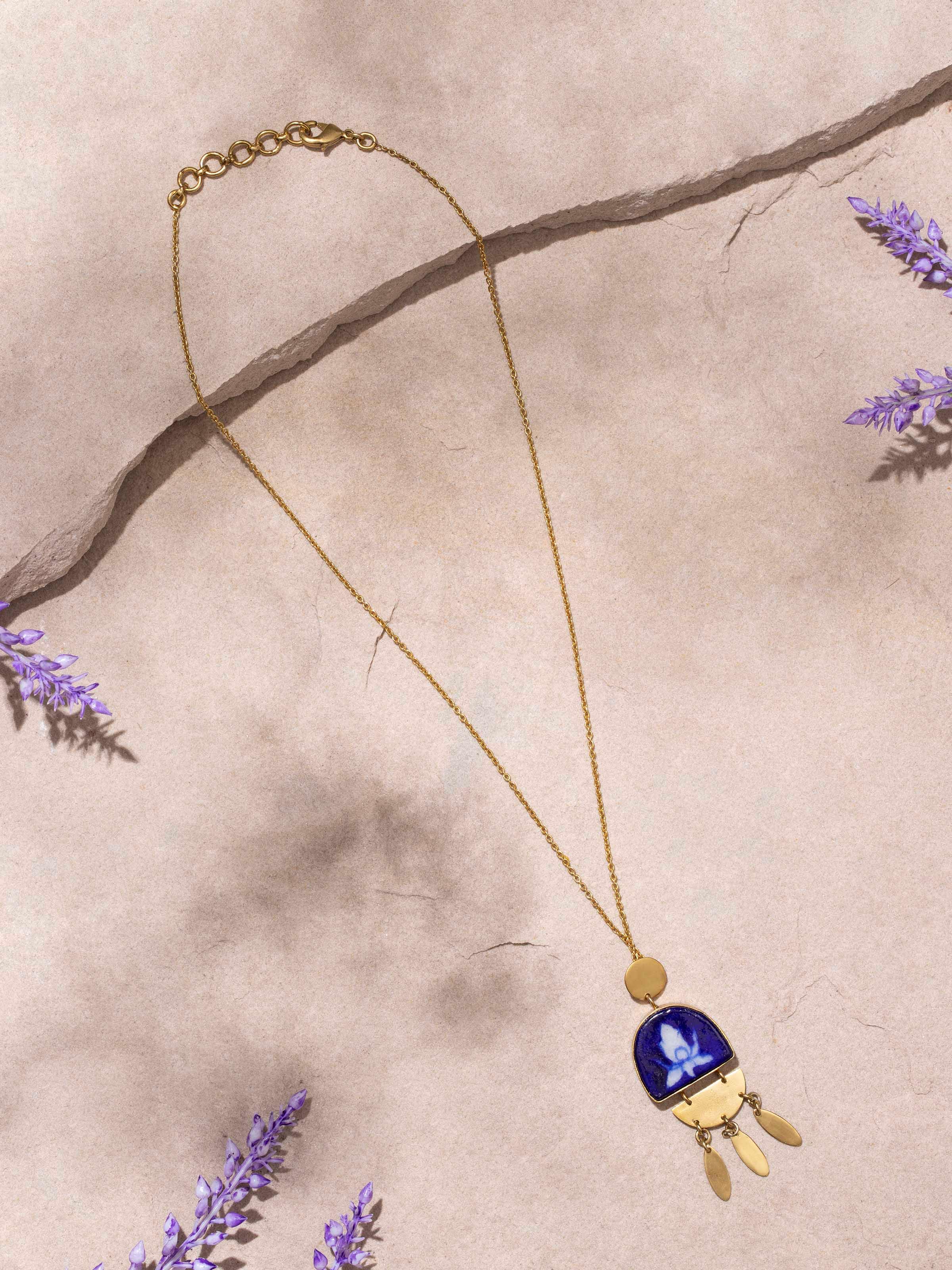 Close-up of Blue pottery pendant showing detailed design and chain linkage.